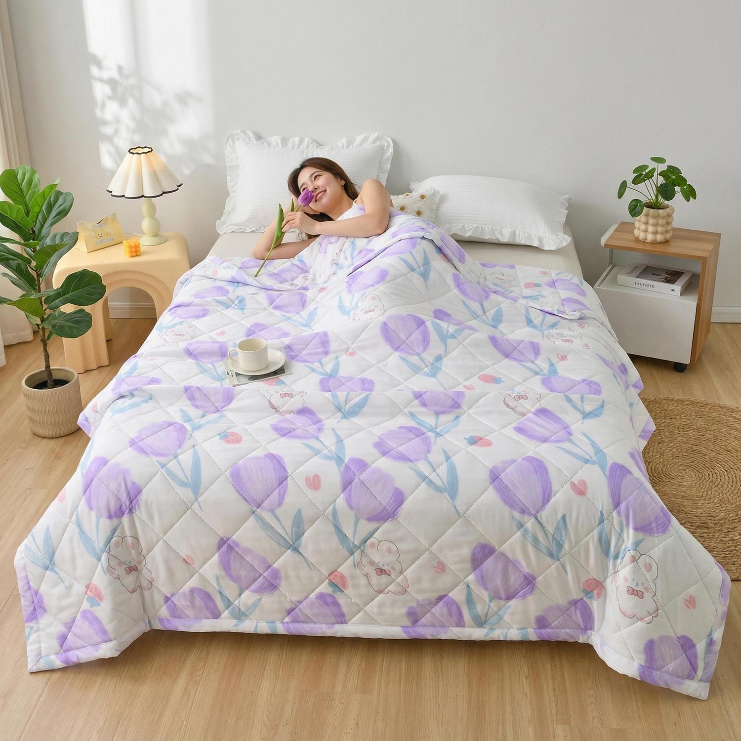 Woman relaxing in bed with a white and purple floral quilted lightweight summer comforter.