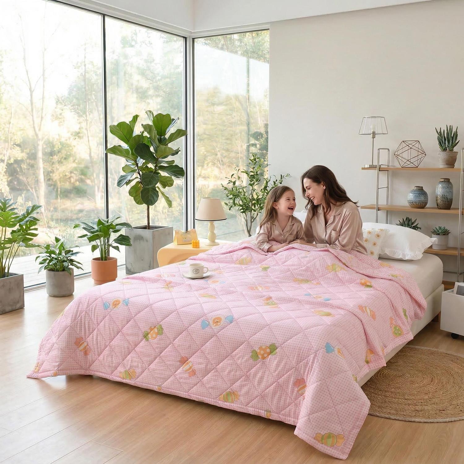 Pink ultrasonic quilted lightweight comforter with colorful fruit pattern, on a bed with a mother and child.