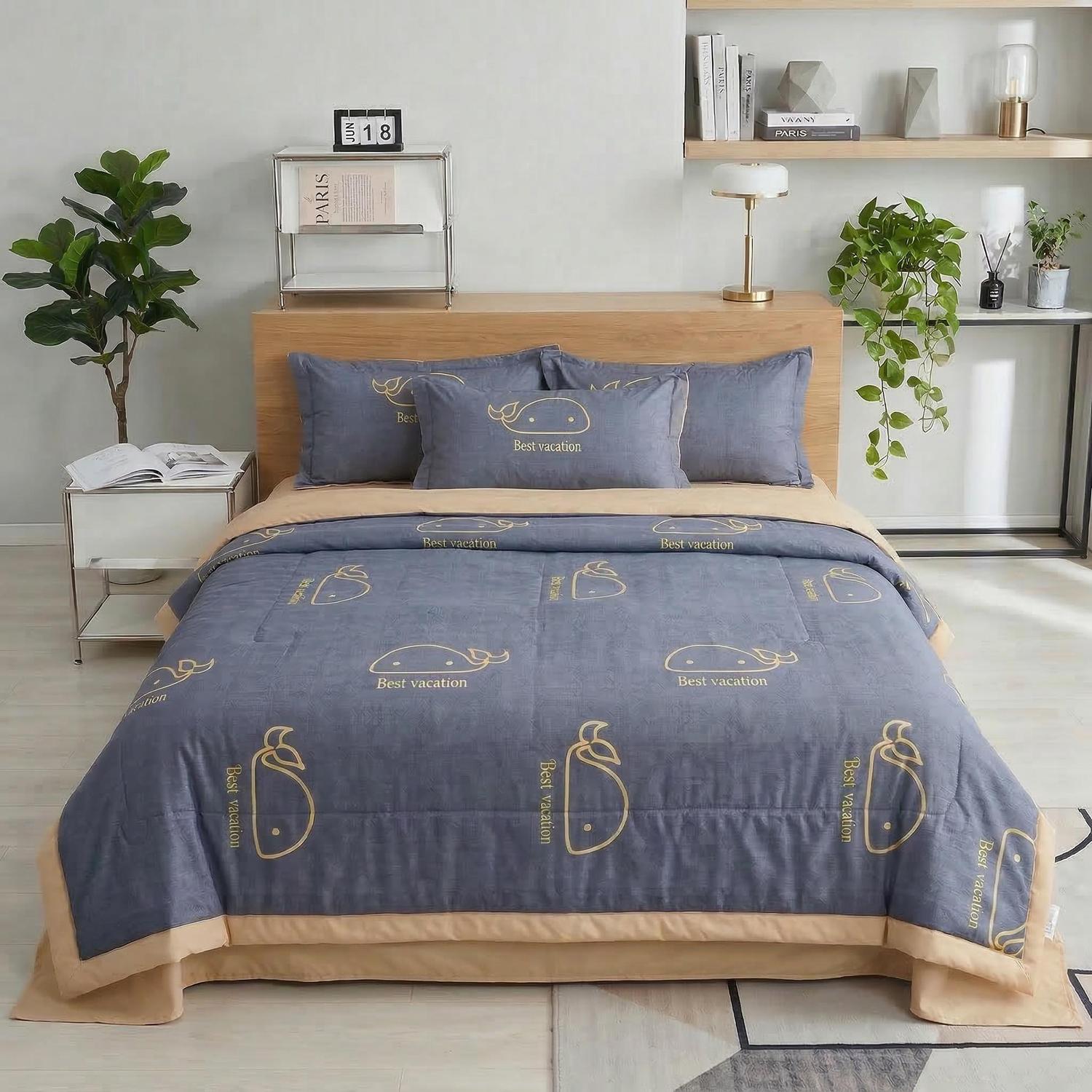 Blue ice silk quilt set with whale and "Best vacation" print, beige trim, on a bed.