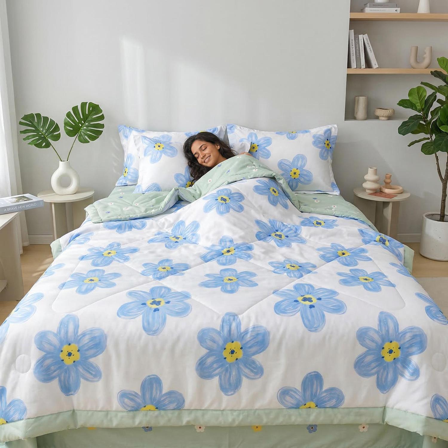 Woman sleeping comfortably in a white ice silk quilt set with blue floral print and light green trim.
