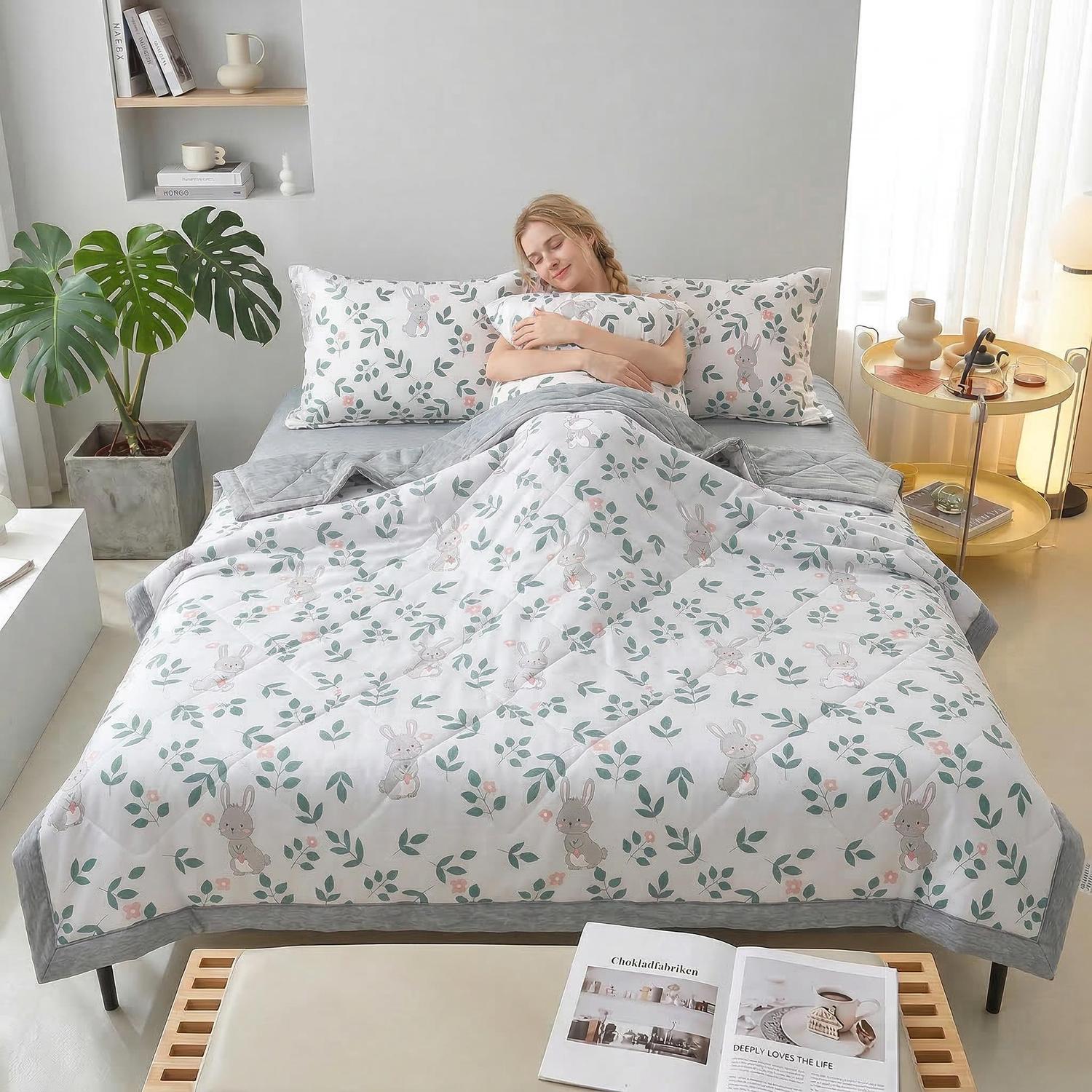 Woman sleeping soundly under a white quilt with green leaf and bunny print, gray trim, and matching pillows.