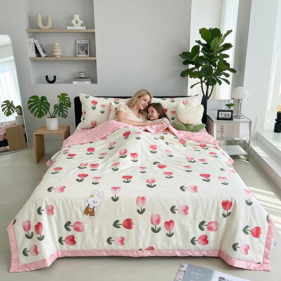 Mother and child on a bed with a white ice silk quilt featuring pink tulip patterns and a bunny.