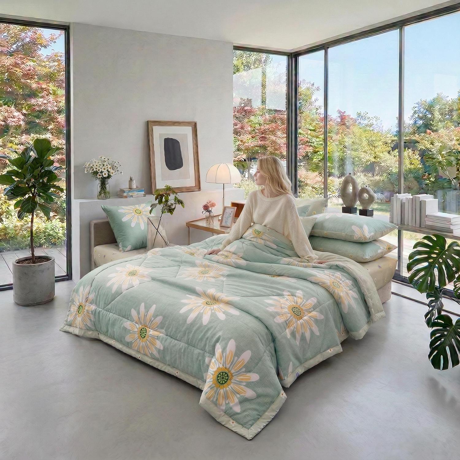 Woman on a bed with a light green cooling quilt blanket featuring yellow and white floral patterns.