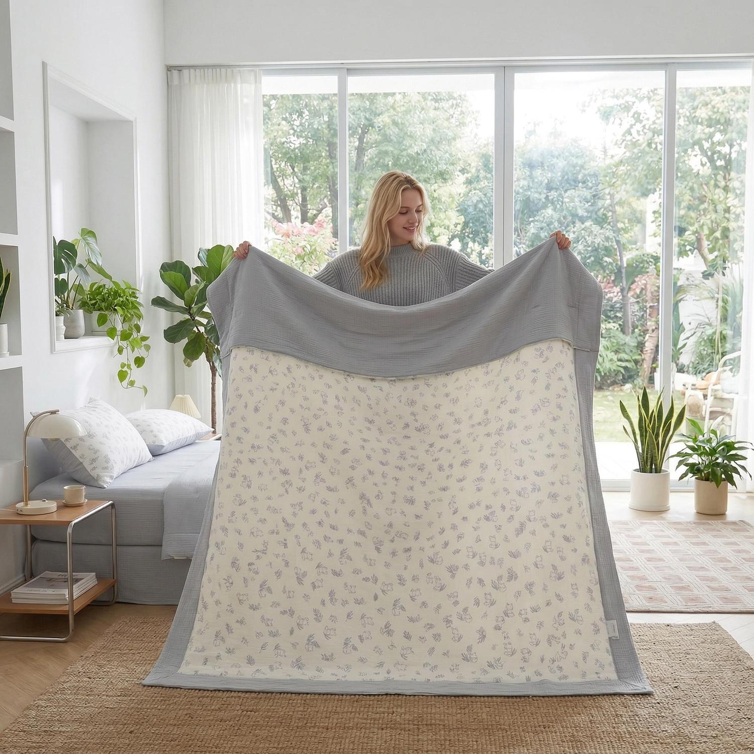 Woman holding a reversible Summer Inspired Quilt Bedding Set with a gray top and a cream floral underside.
