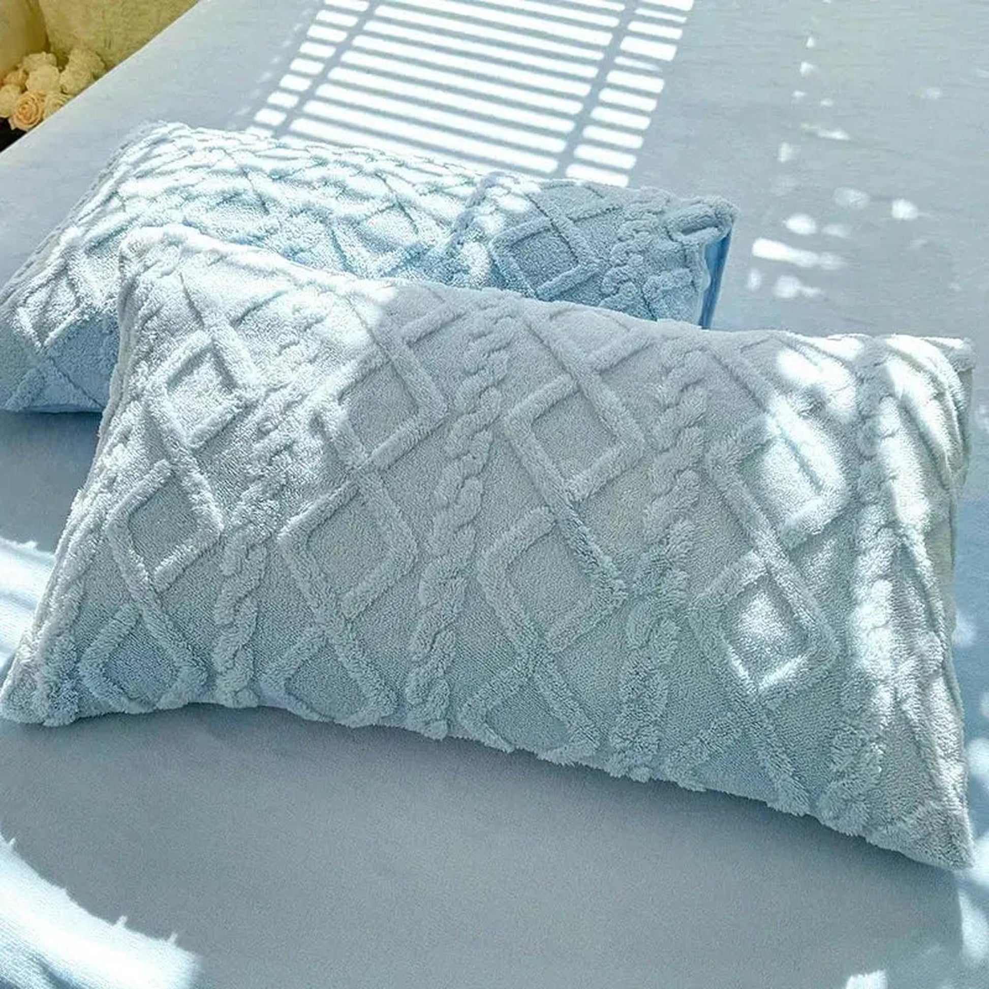 Set of two light blue textured velvet pillowcases with a diamond and braid pattern.