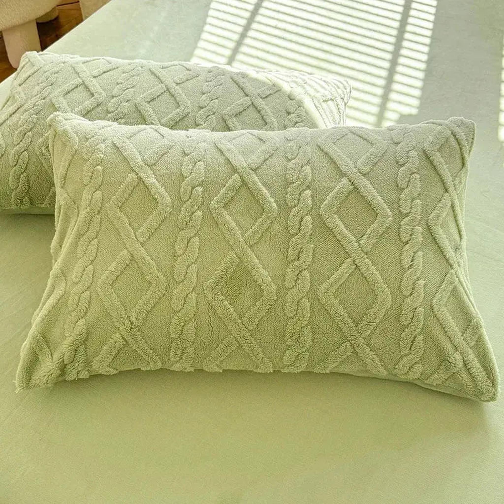 Set of two sage green textured velvet pillowcases with a cable knit diamond pattern.