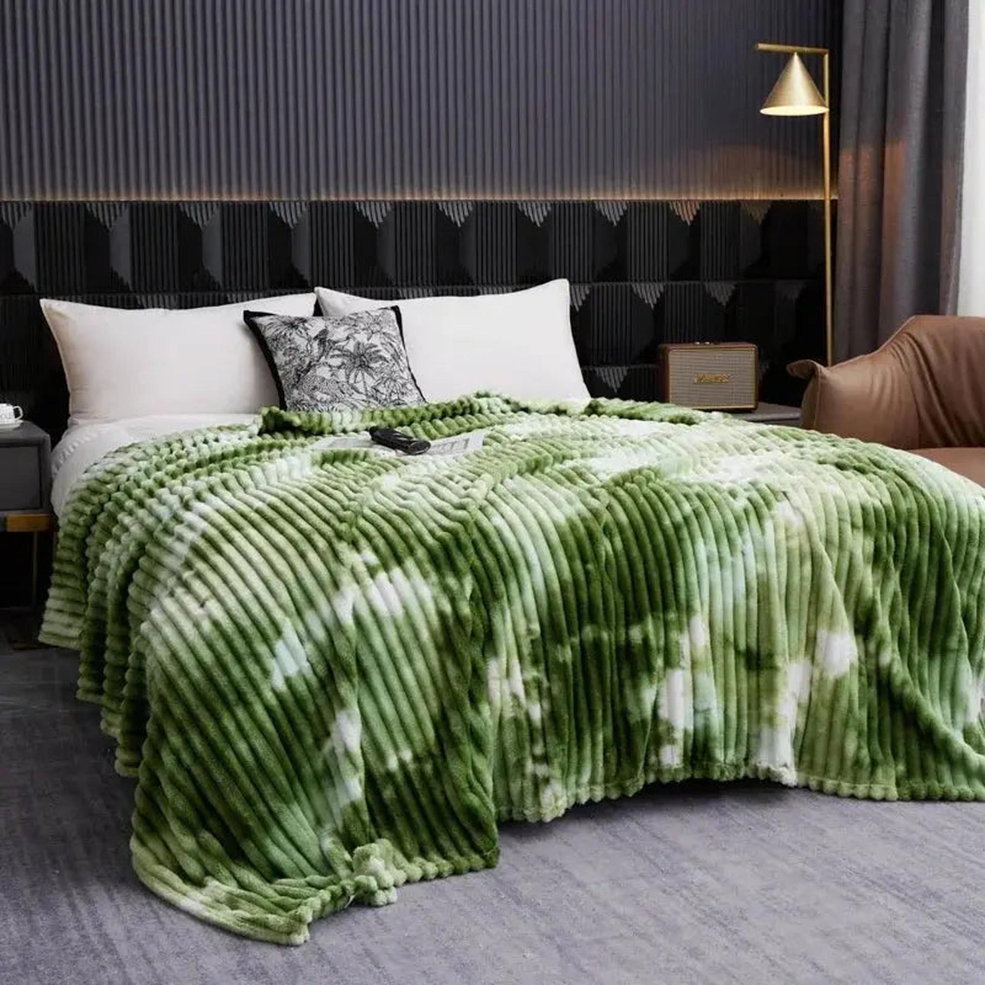 Green and white tie-dye flannel fleece blanket with a ribbed texture draped on a bed.