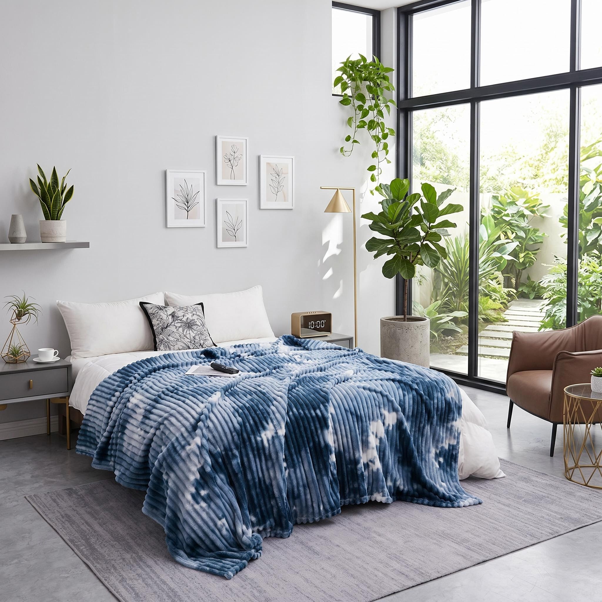 Blue and white tie-dye flannel fleece blanket draped on a bed in a bright room.