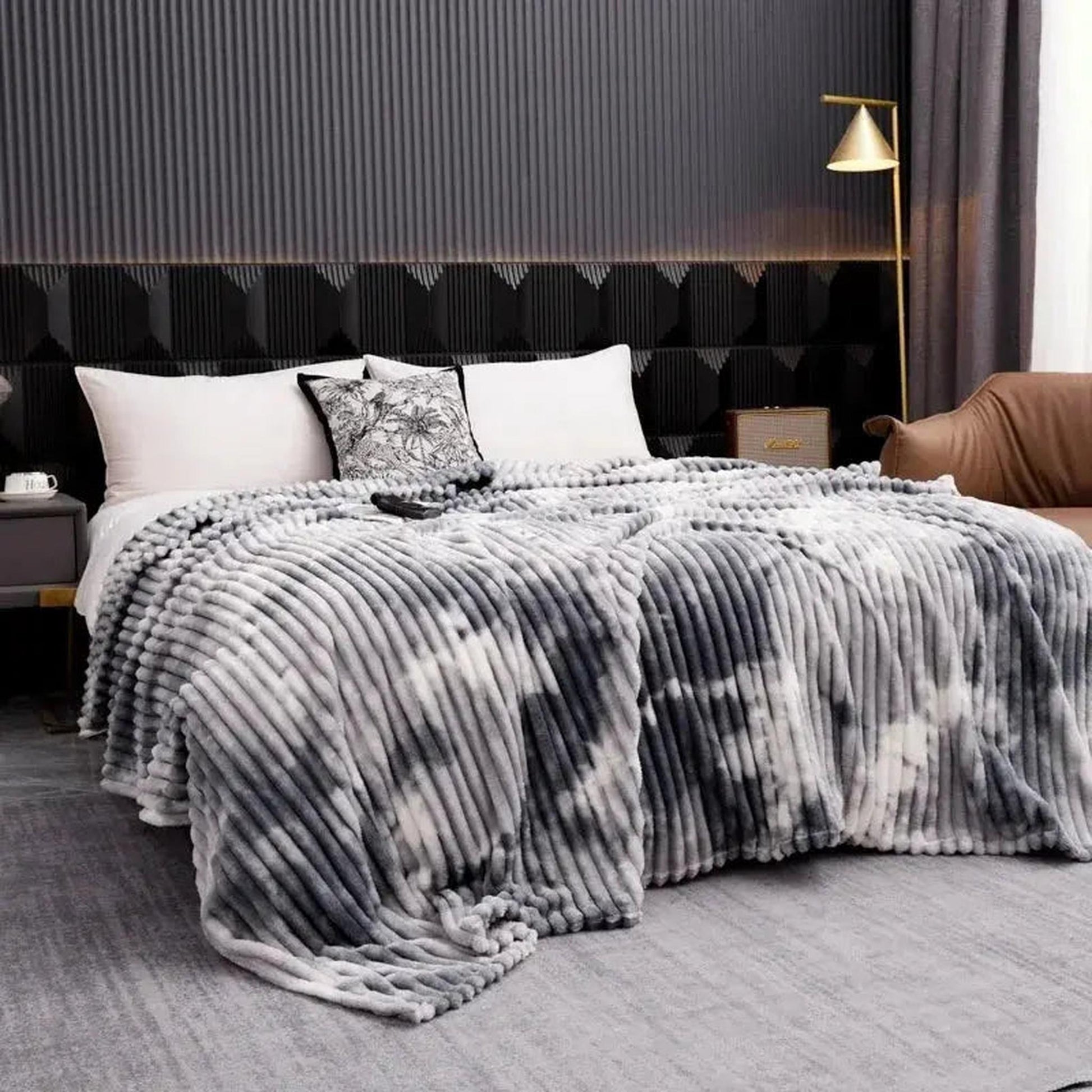 Gray and white tie-dye flannel fleece blanket with ribbed texture draped on a bed.