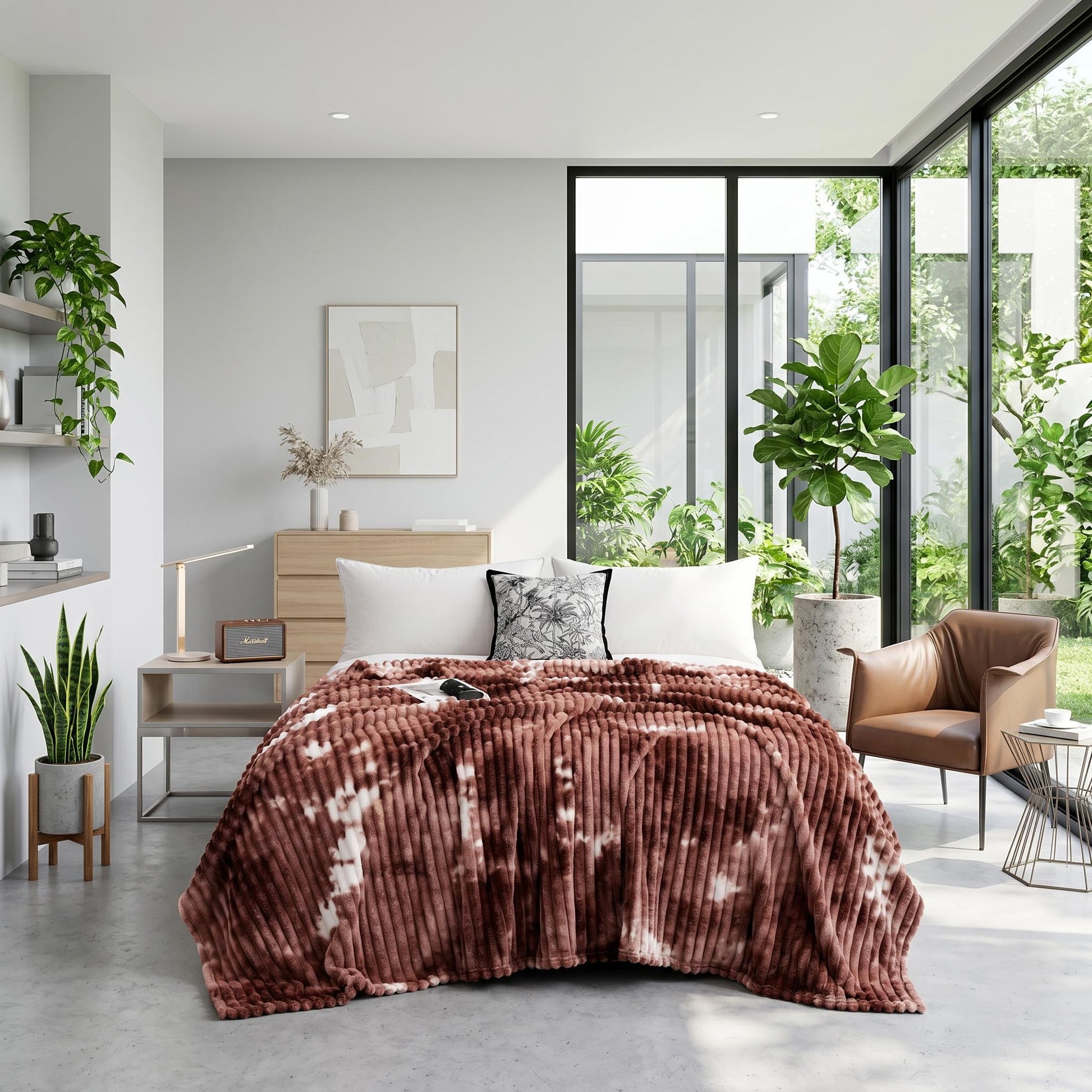 Brown tie-dye flannel fleece blanket draped on a bed in a modern, plant-filled bedroom.