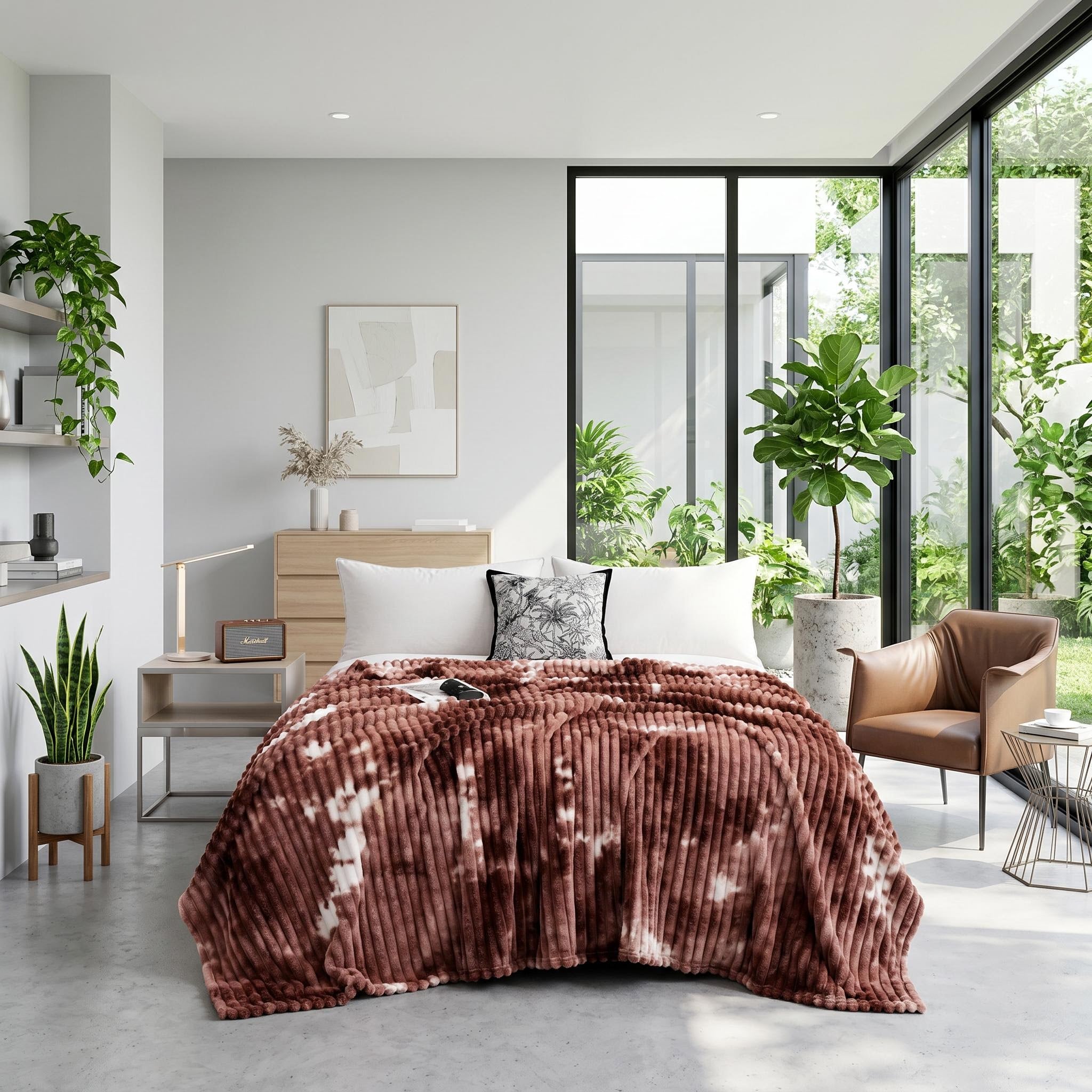 Brown tie-dye flannel fleece blanket draped on a bed in a modern, plant-filled bedroom.