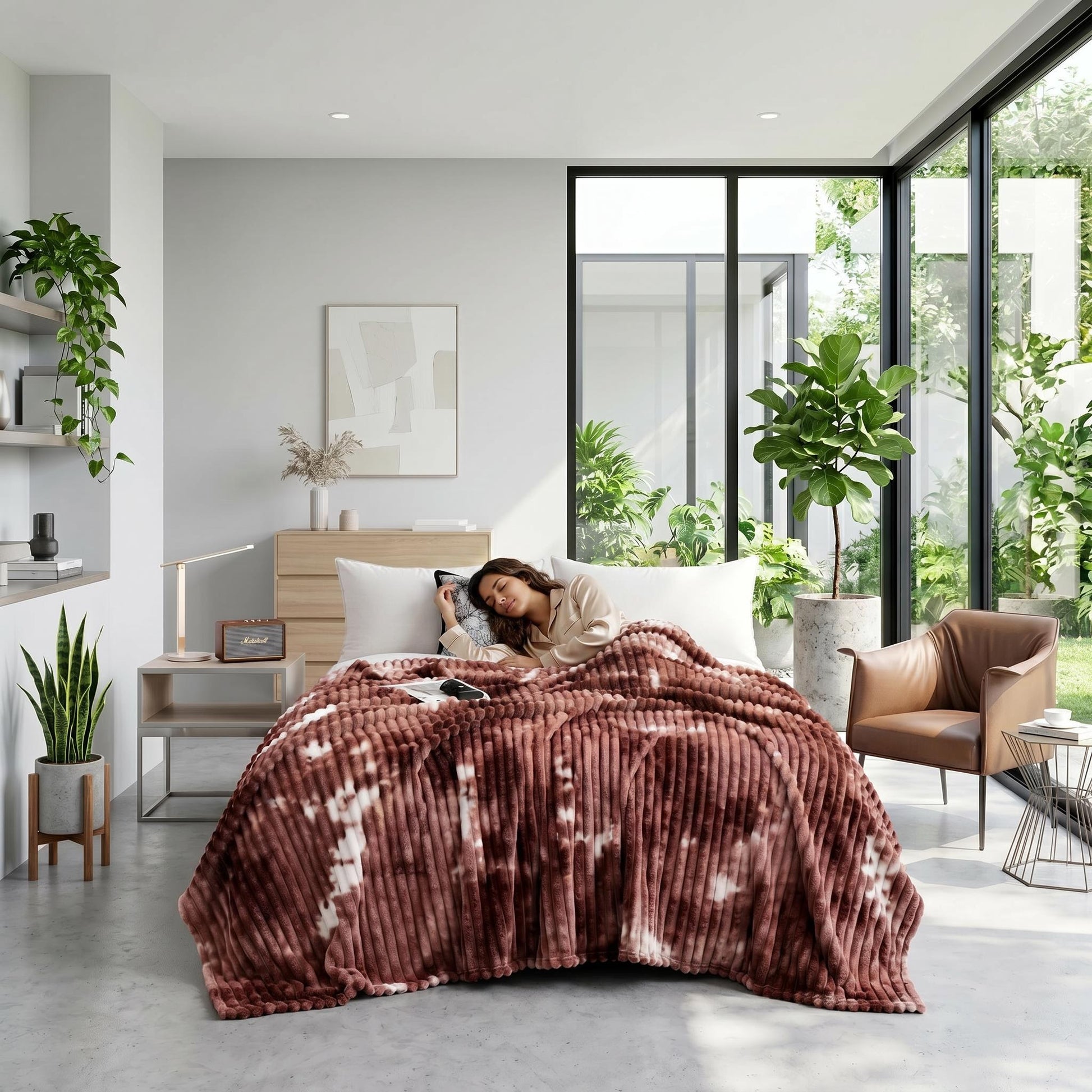Woman sleeping under a plush, brown and white tie-dye flannel fleece blanket in a modern, plant-filled bedroom.
