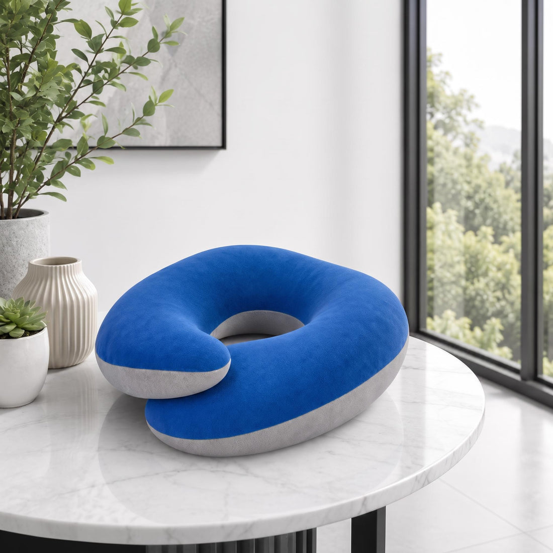 Woman wearing a blue and grey ergonomic travel neck pillow and black sleep mask while resting in an airplane seat.