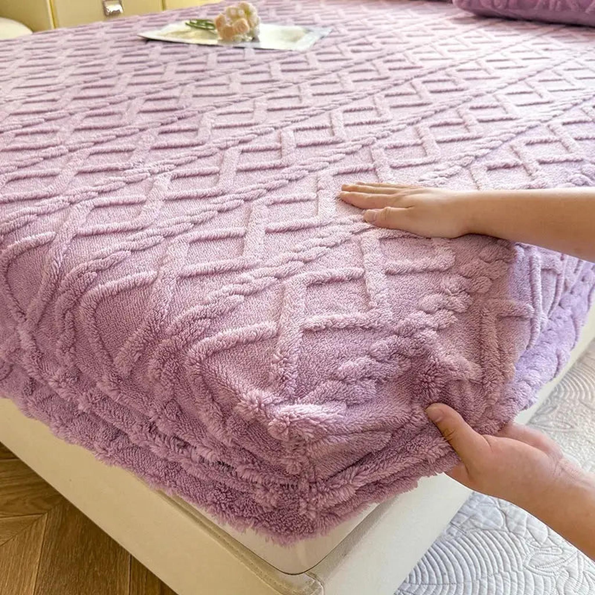 Lavender coral fleece fitted bed sheet with a textured ribbed pattern, being smoothed by hands.