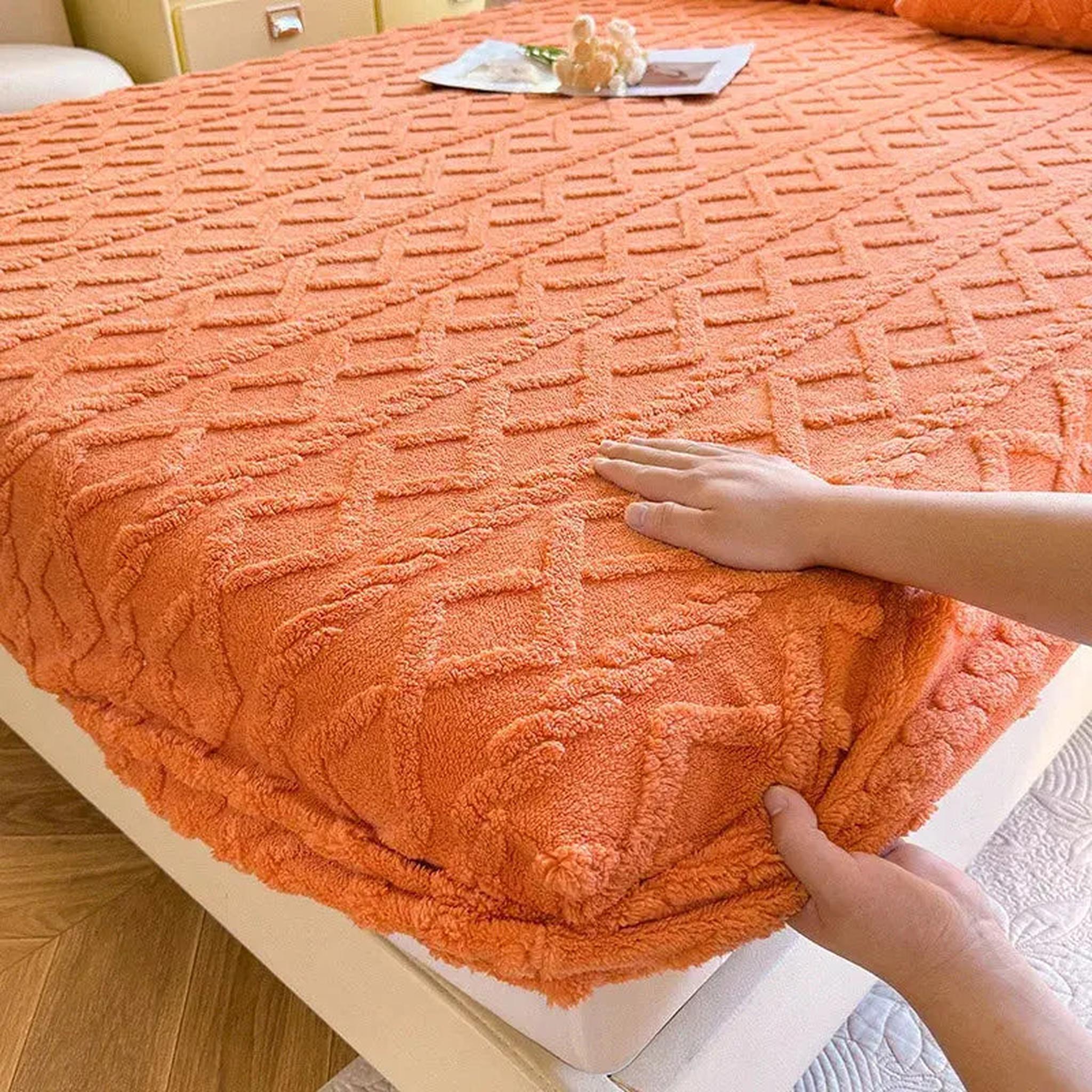Warm coral fleece fitted bed sheet with a textured ribbed pattern, shown being adjusted on a mattress.