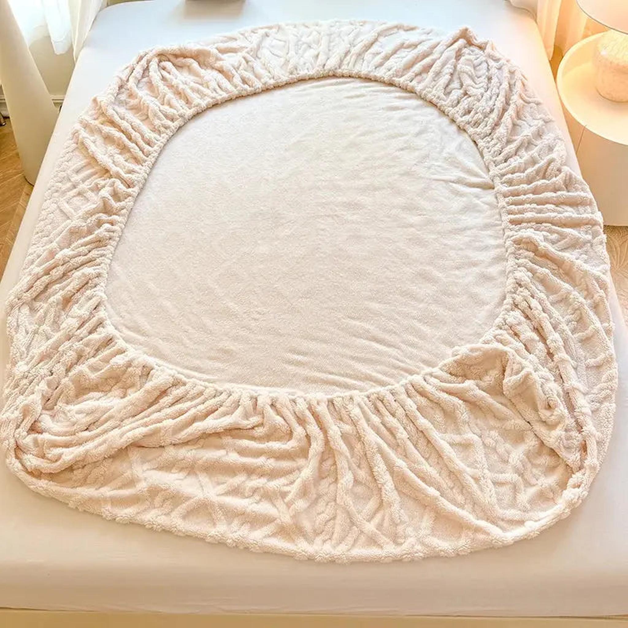 Light pink coral fleece fitted bed sheet with textured ribbed fabric and elasticized edges.