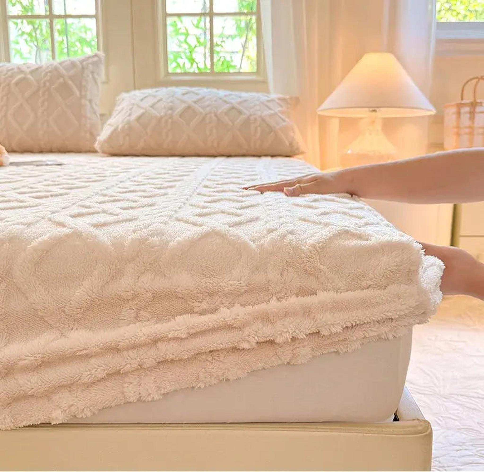 Hand adjusting a cream coral fleece fitted bed sheet with a textured ribbed pattern on a mattress.