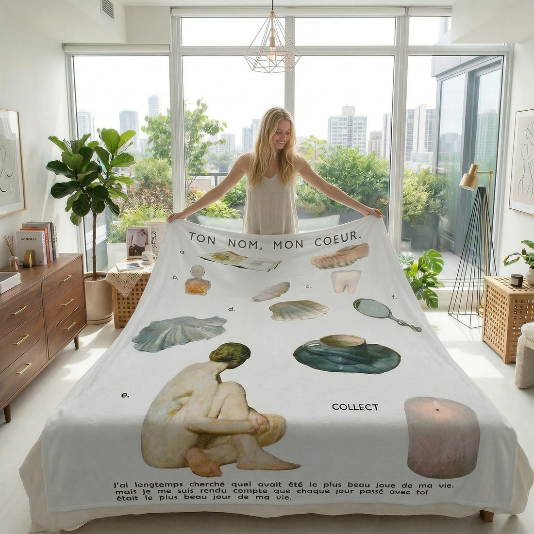 Woman reading in bed, covered by a white Vikama flannel blanket with artistic nude figures and French text.