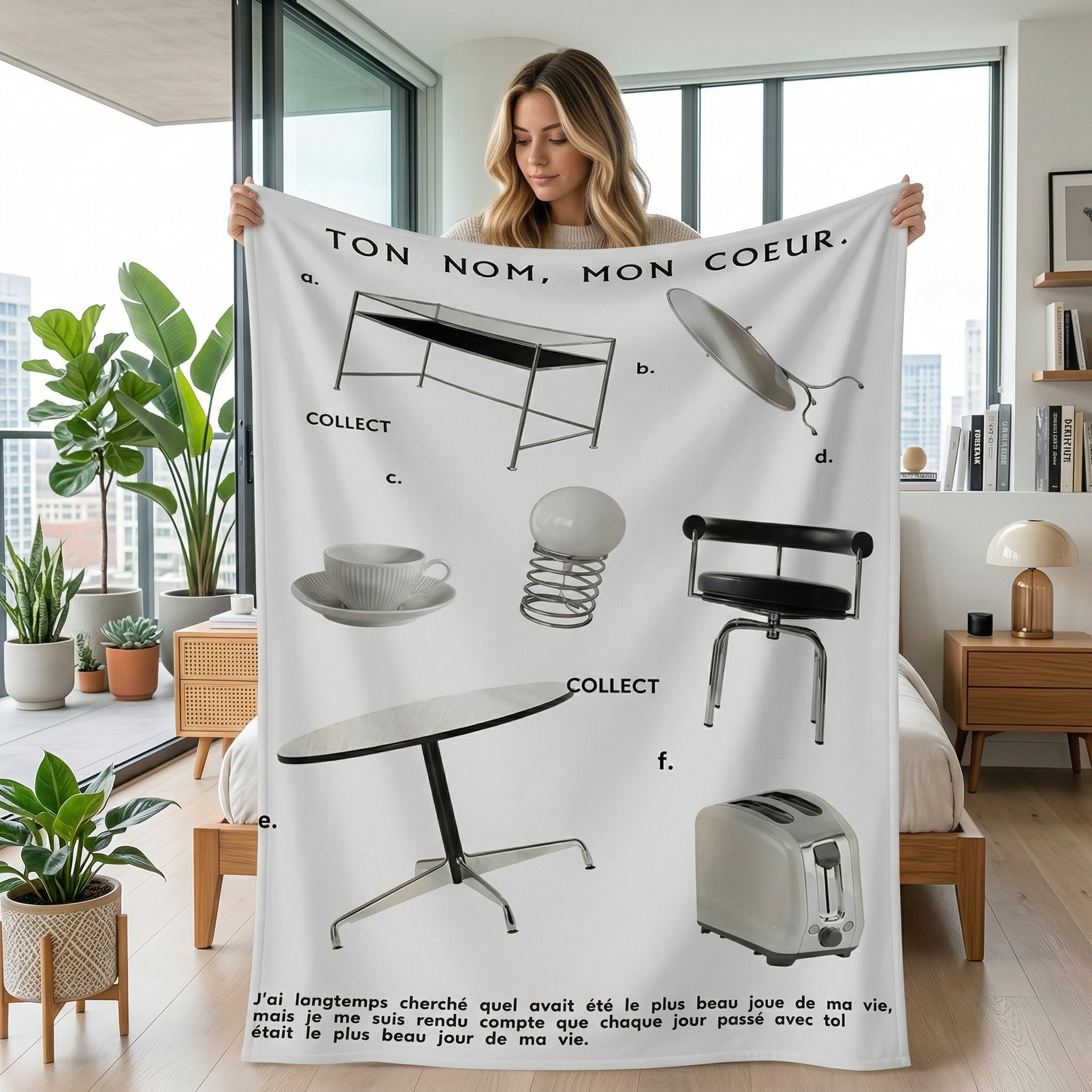 Woman holding a white Vikama Flannel Blanket with black text and illustrations of vintage furniture and a toaster.