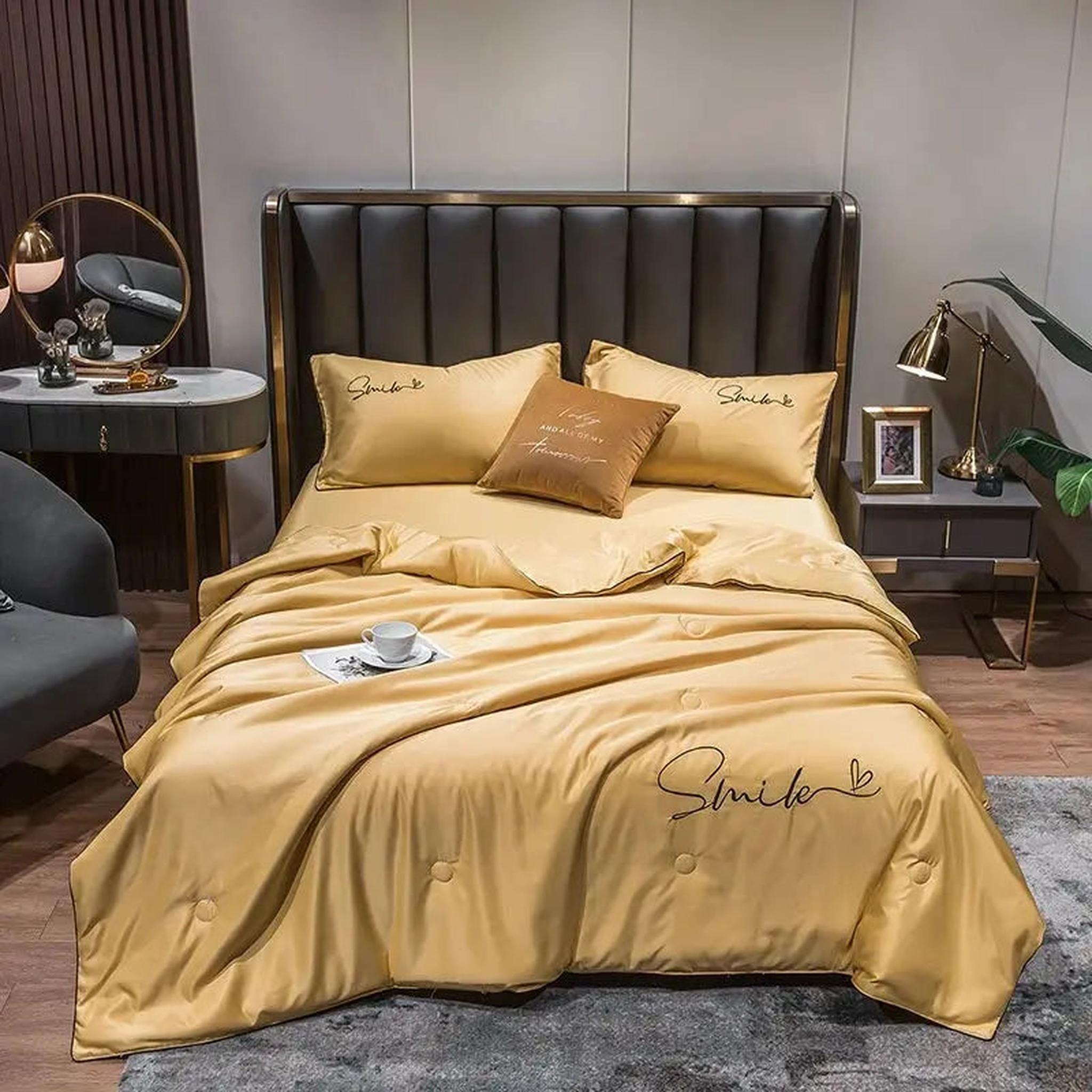 Golden washed silk summer quilt set with "Smile" embroidery on a bed.