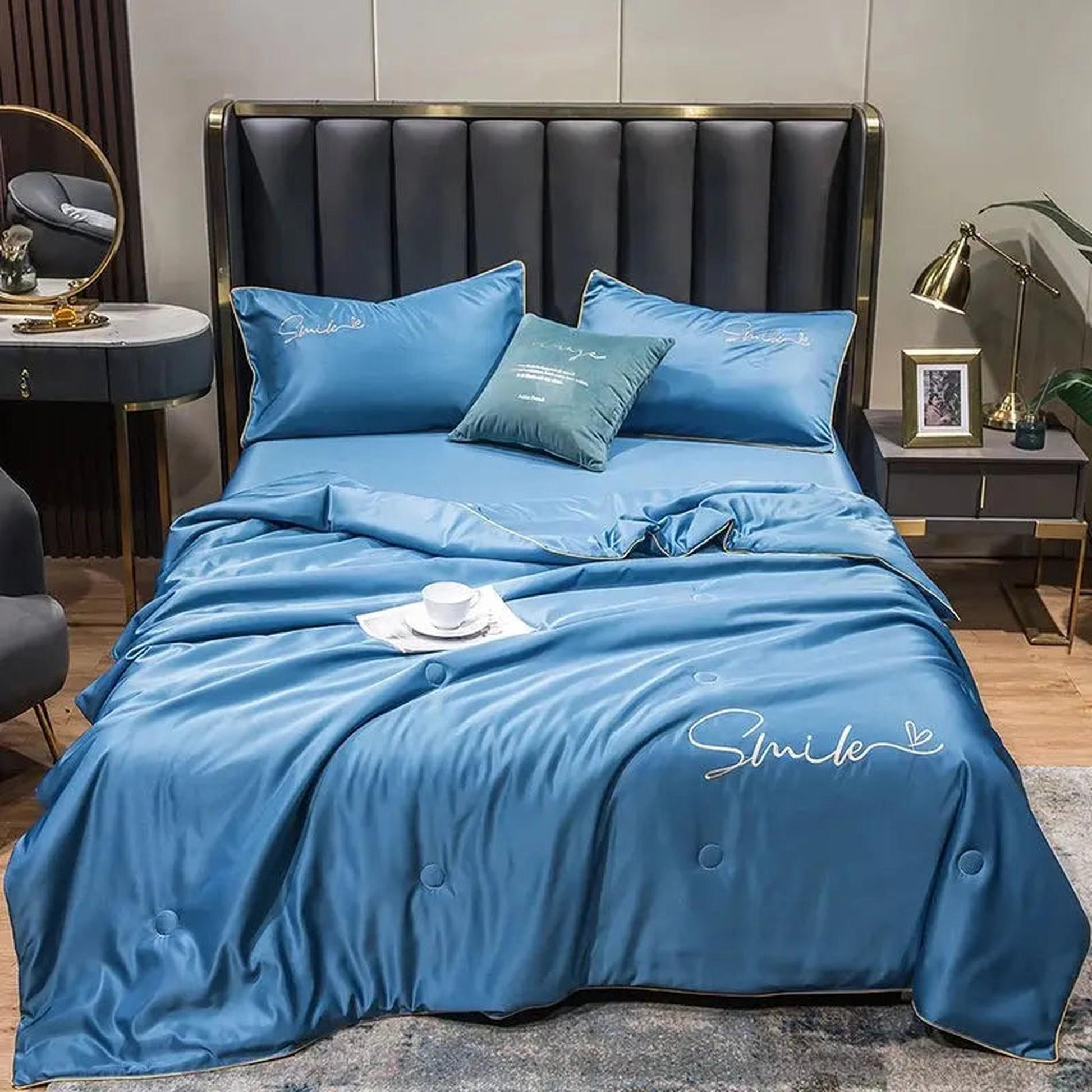 Blue washed silk summer quilt set with embroidered "Smile" text and two pillowcases on a bed.