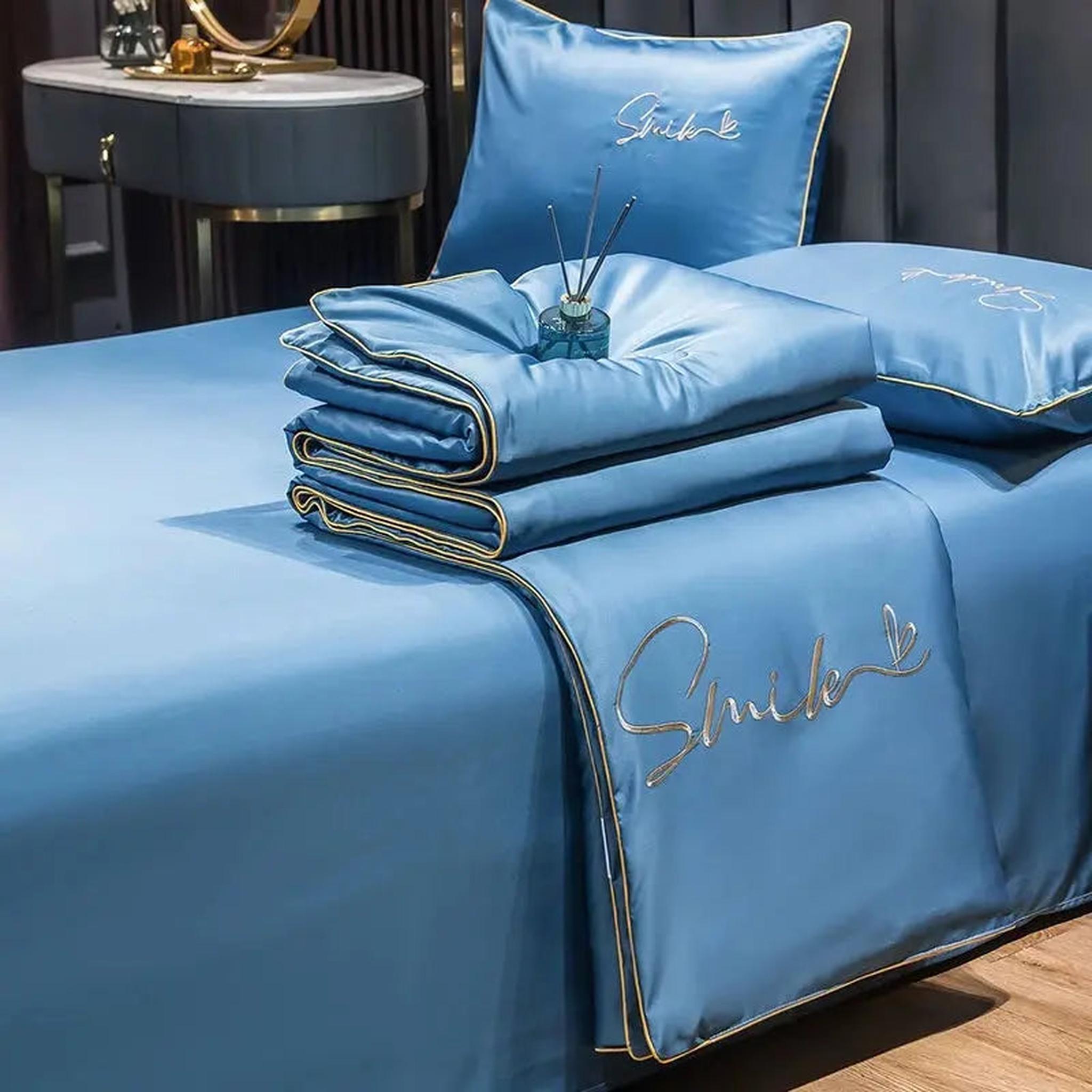 Blue washed silk summer quilt set with gold embroidered "Smile" text and trim.