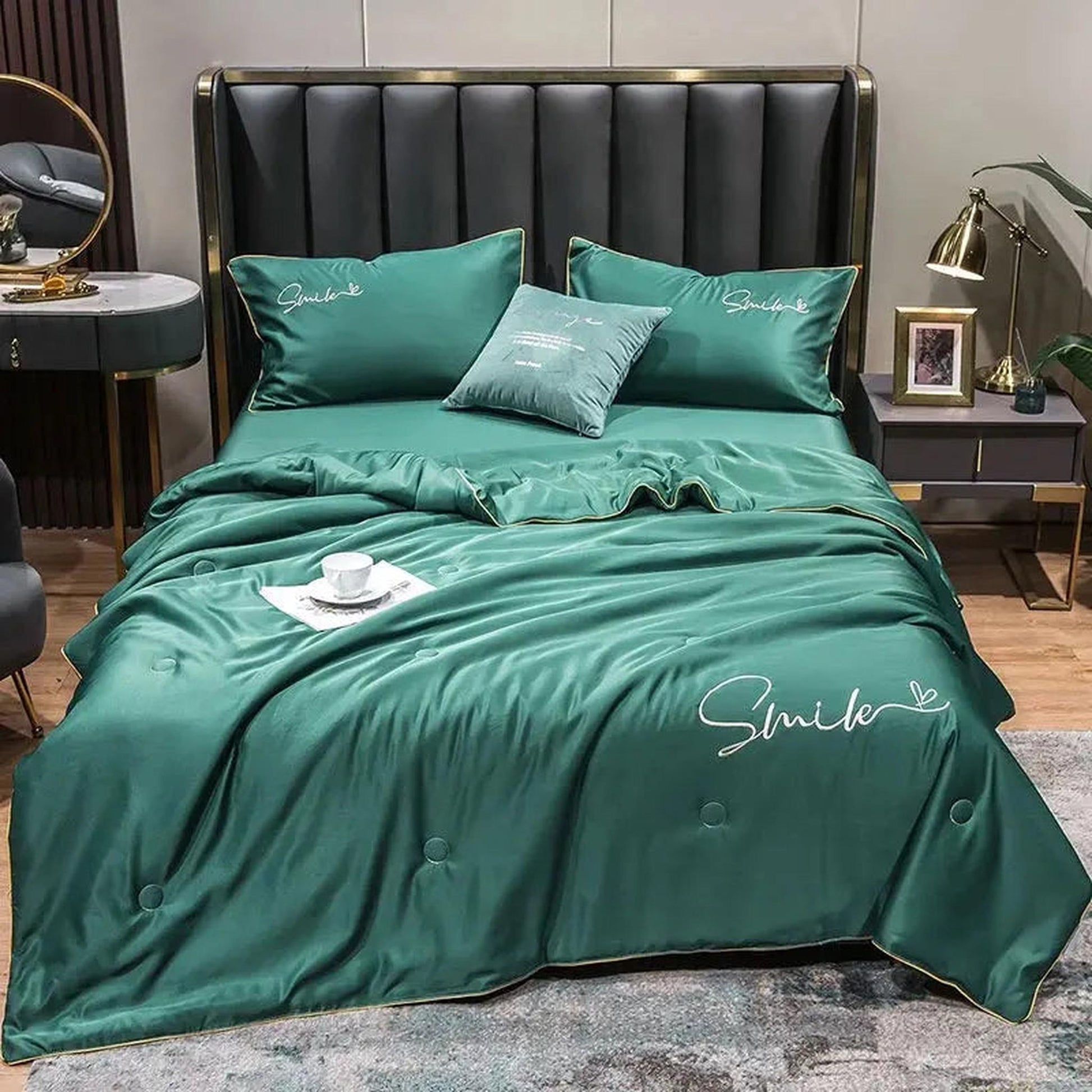 Emerald green washed silk quilt set with "Smile" embroidery and gold trim on a modern bed.