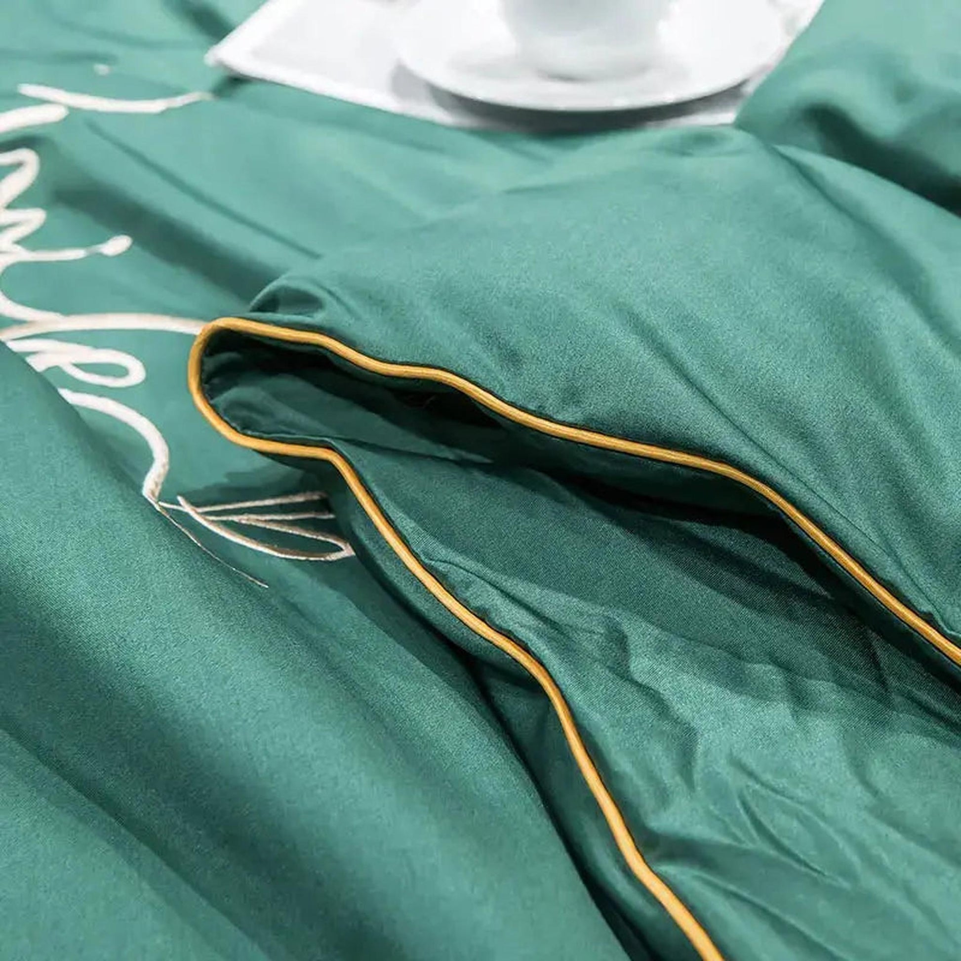 Emerald green washed silk quilt with subtle white embroidery and gold piping.