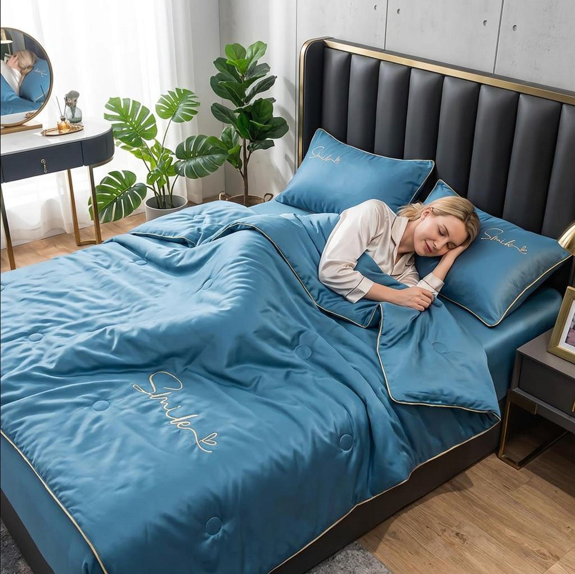 Woman sleeping soundly under a blue washed silk summer quilt set with "Smile" embroidery and gold piping.