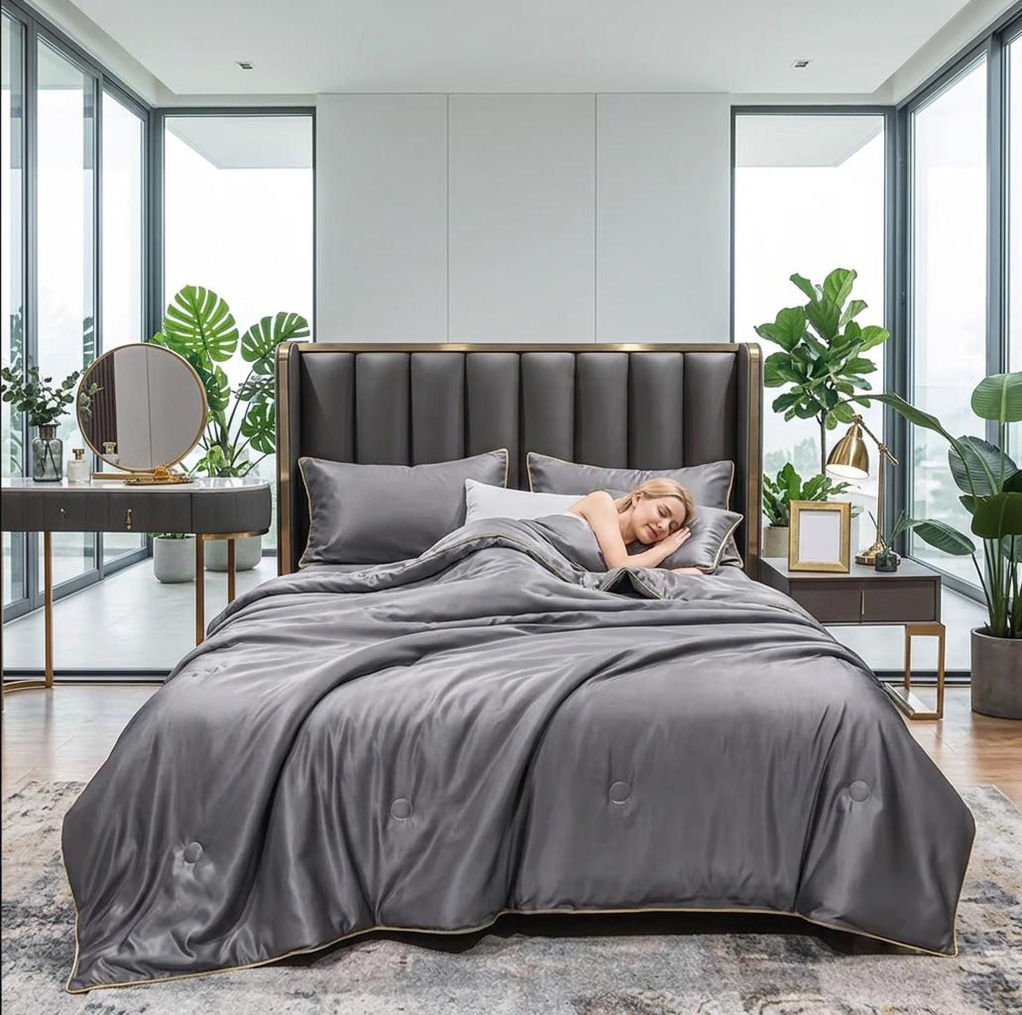 Gray washed silk summer quilt set with embroidered trim on a bed in a modern bedroom.