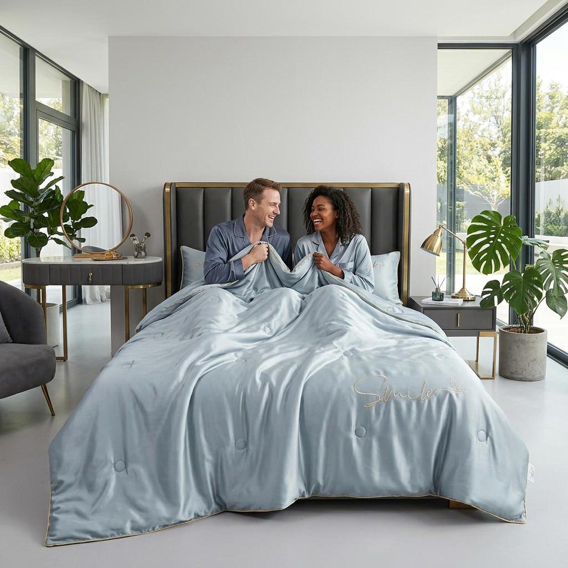 Light blue washed silk summer quilt set with gold embroidered "Smile" text, on a bed with two people.