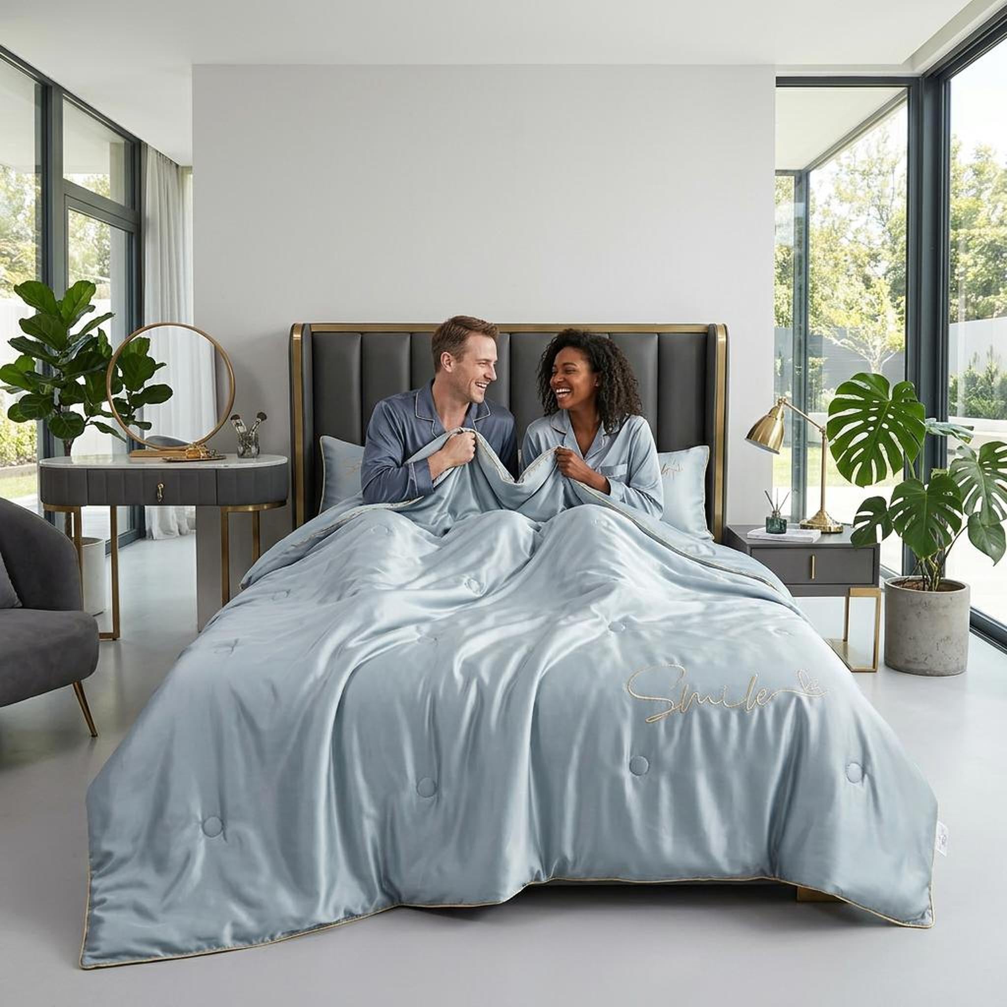 Light blue washed silk summer quilt set with gold embroidered "Smile" text, on a bed with two people.