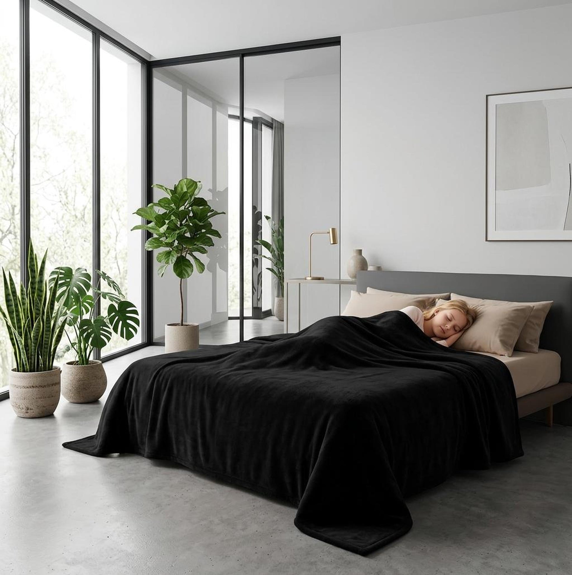 Woman sleeping soundly under a dark moon grey waterproof flannel fleece blanket in a modern bedroom.