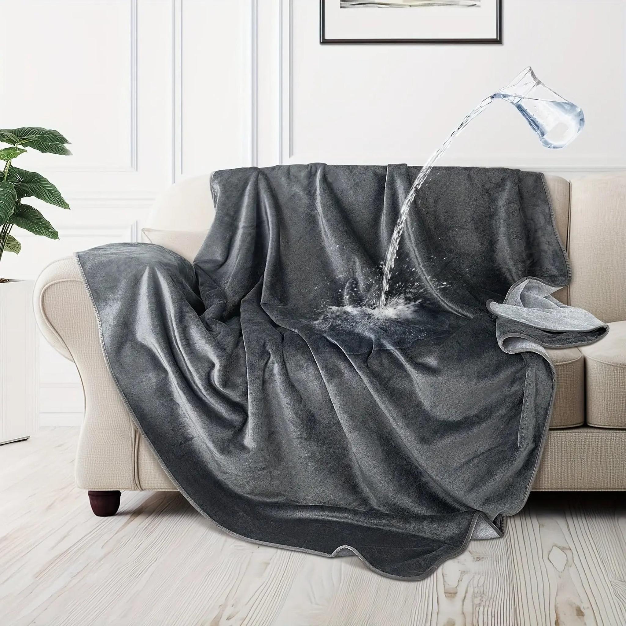 Waterproof dark moon grey flannel fleece blanket on a couch, repelling spilled water.