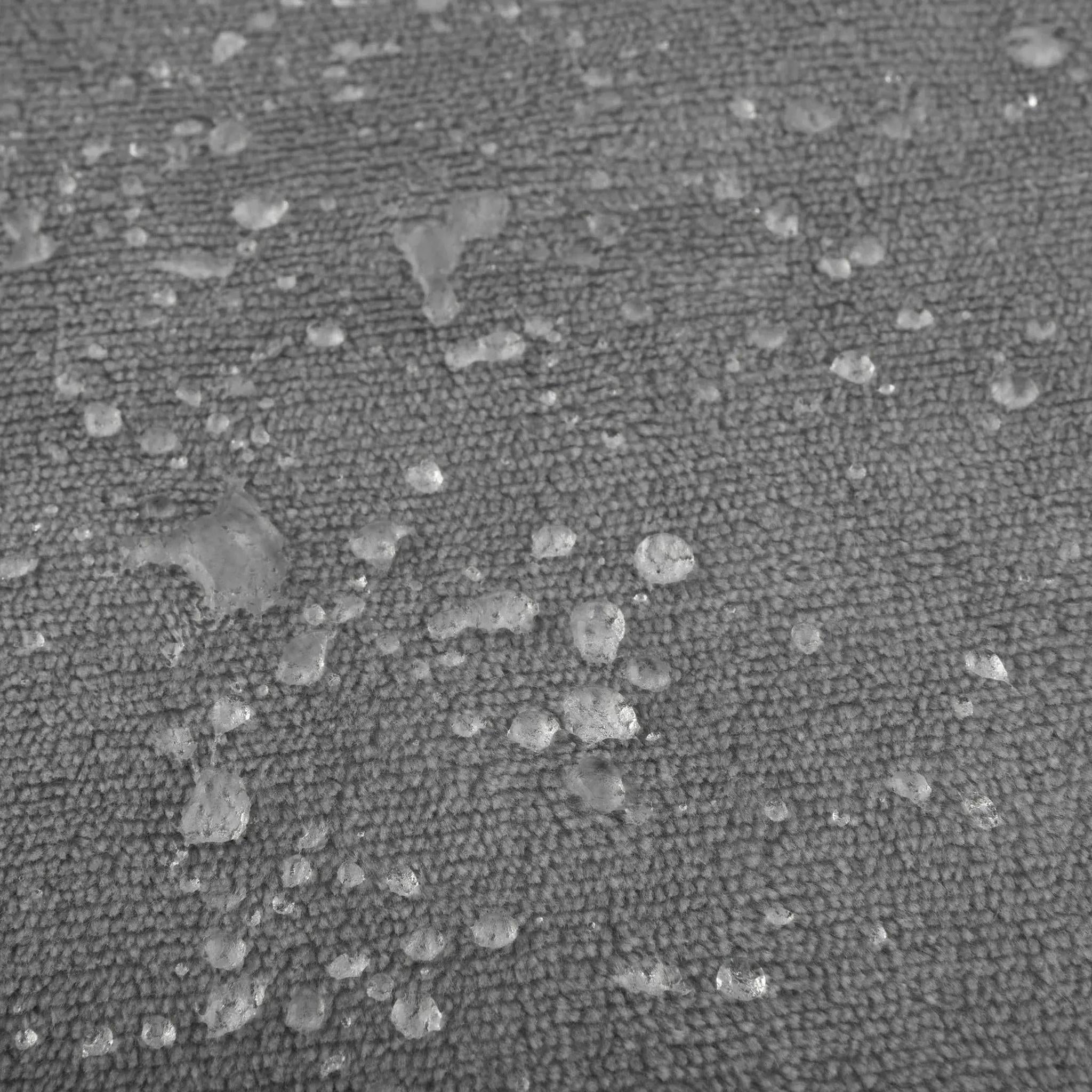 Close-up of a dark moon grey waterproof flannel fleece blanket with water beads on its surface.