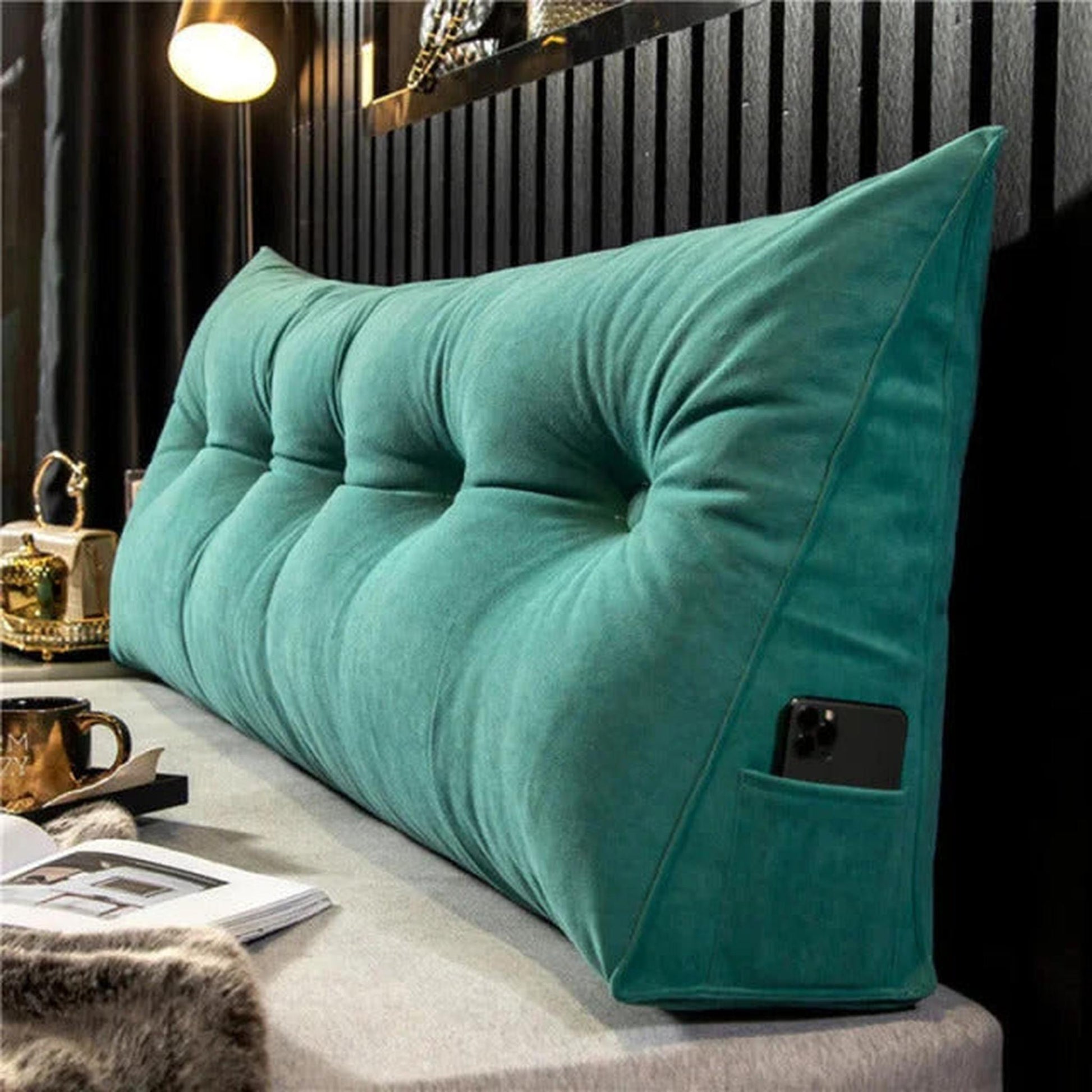 Green organic cotton wedge pillow with tufted design and side pocket holding a phone.