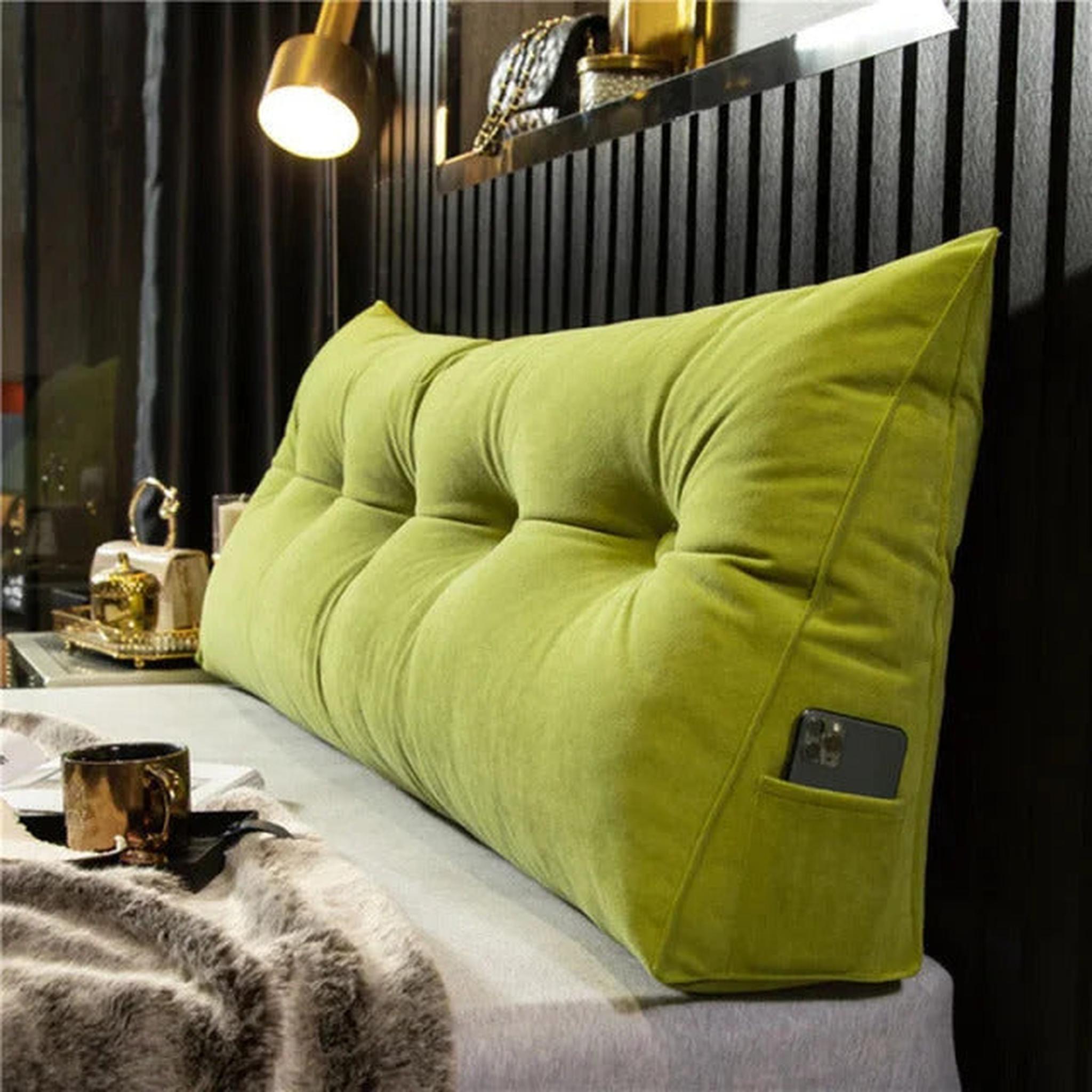 Lime green wedge pillow with tufted design and side pocket for phone, on a bed.