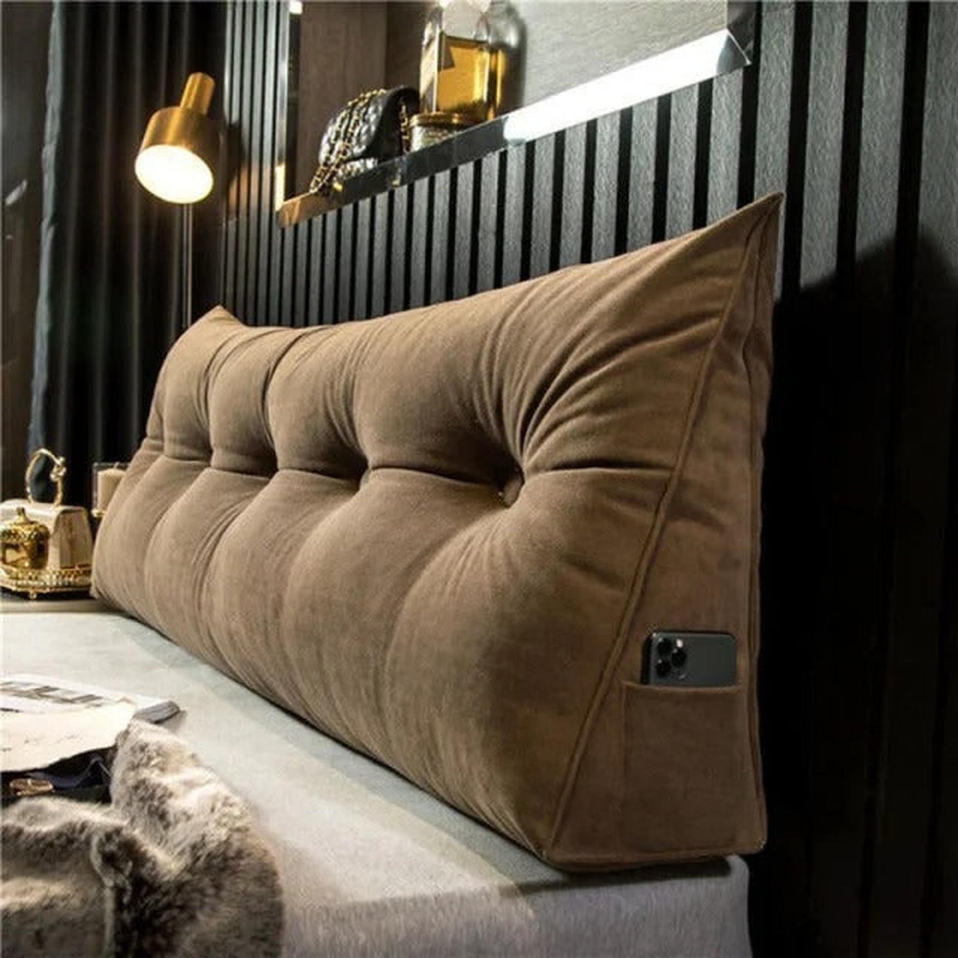 Brown tufted wedge pillow for back support with a side pocket holding a phone.