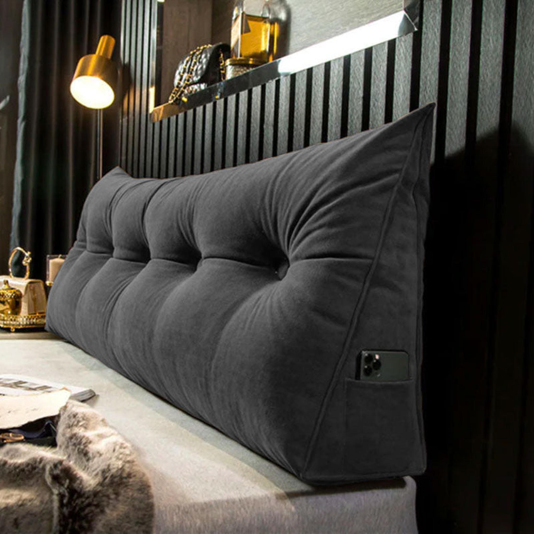 Dark gray tufted wedge pillow for back support with a side pocket holding a phone.