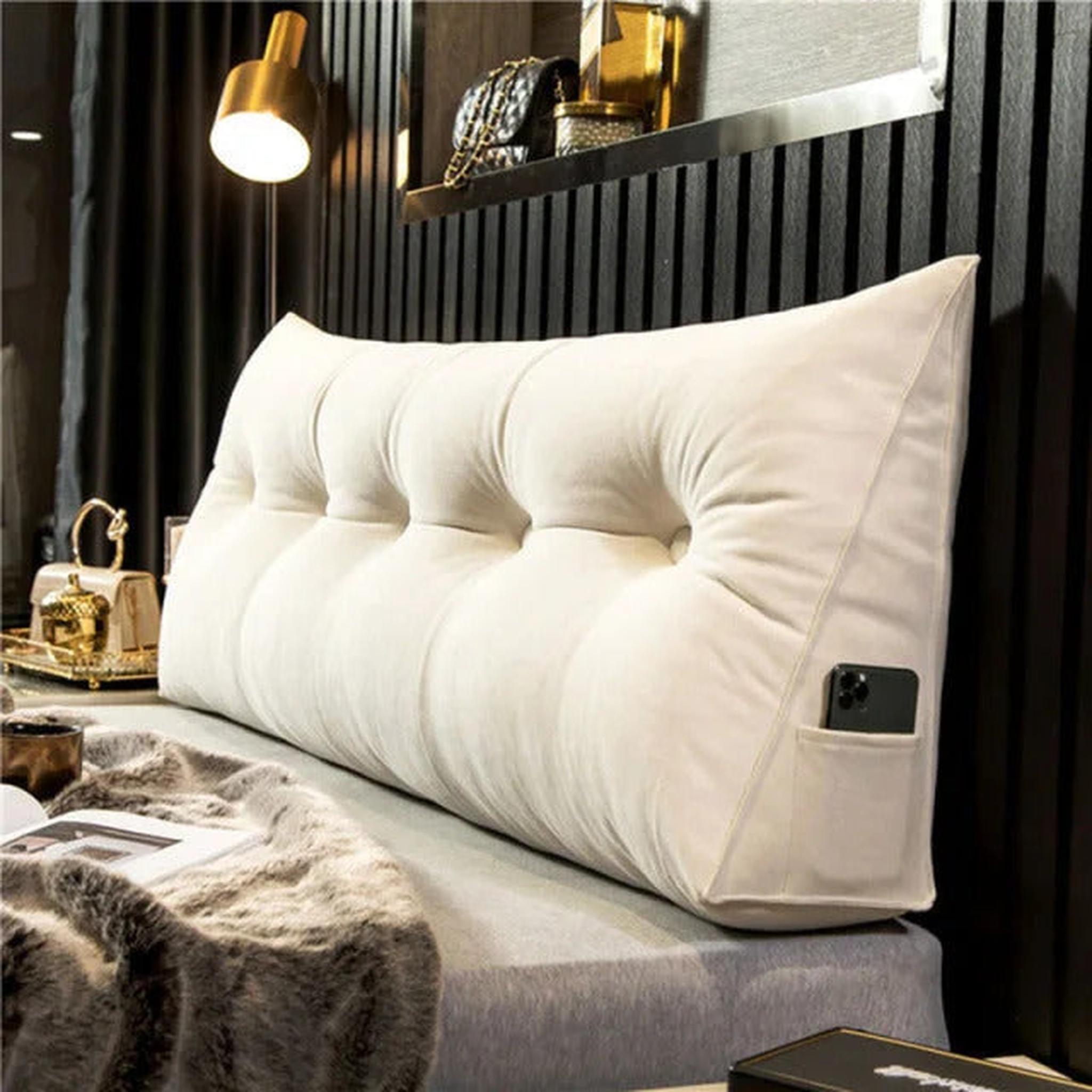 Cream organic cotton wedge pillow with tufted design and side pocket holding a phone.