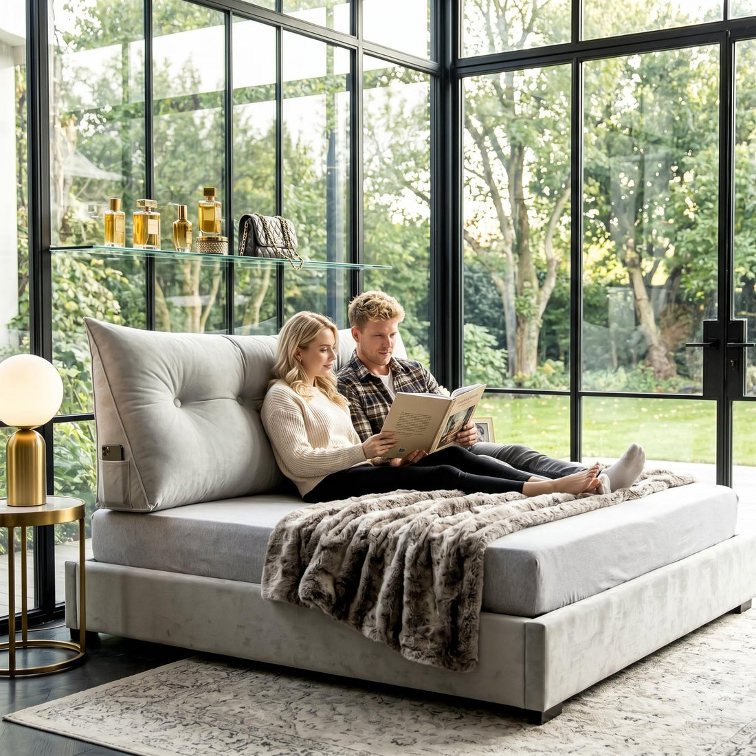 Light gray wedge pillow with tufted button detail and side pocket supporting a couple reading on a bed.