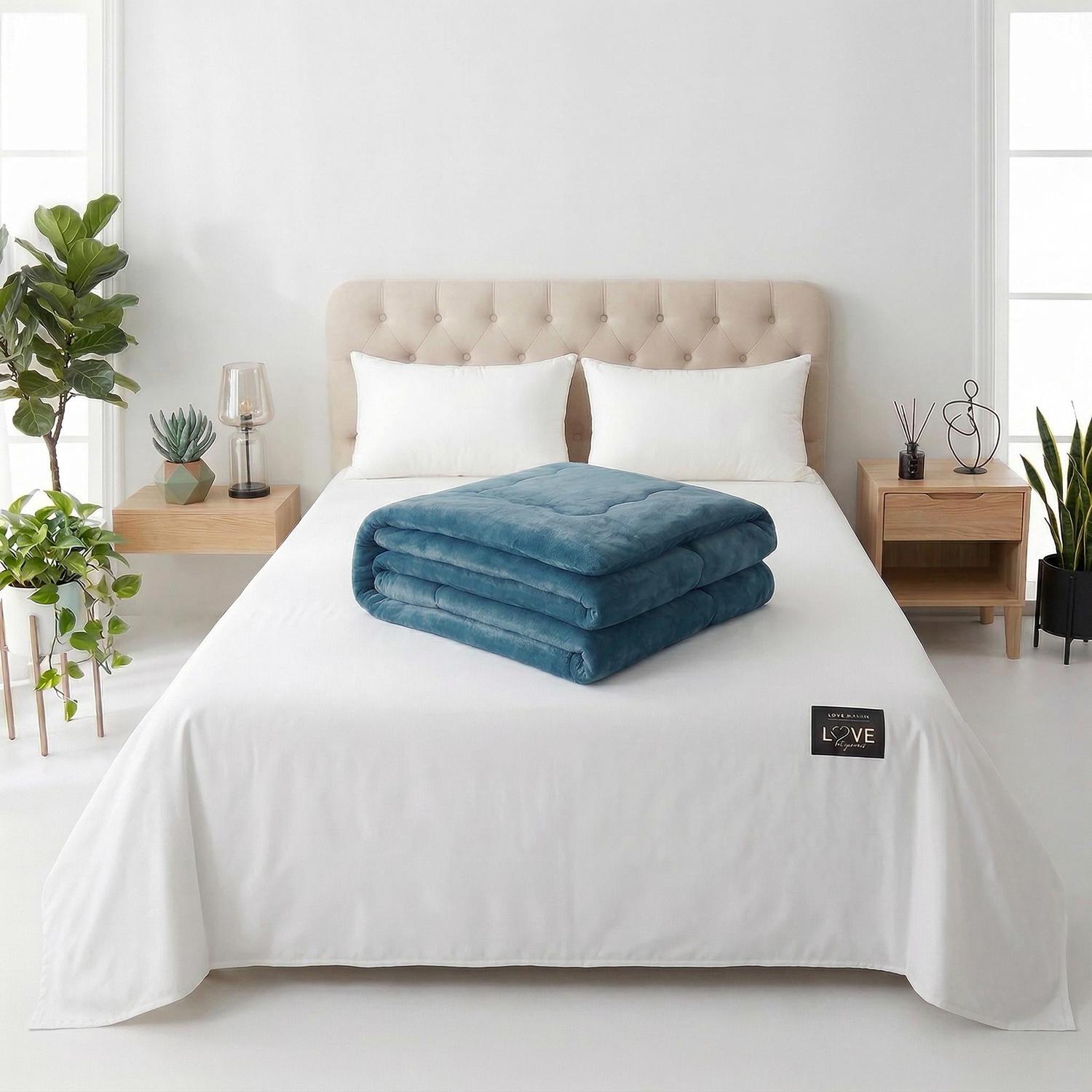 Folded teal quilted polyester blanket on a white bed, enhancing a cozy bedroom setting.