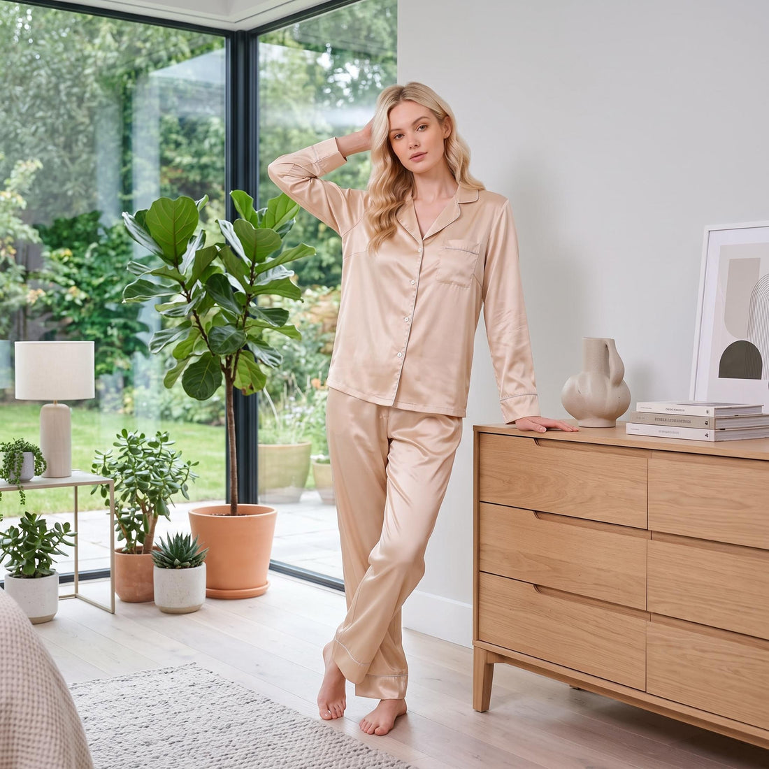 Woman wearing a champagne-colored mulberry silk long-sleeve pajama set with a notched collar and contrast piping.