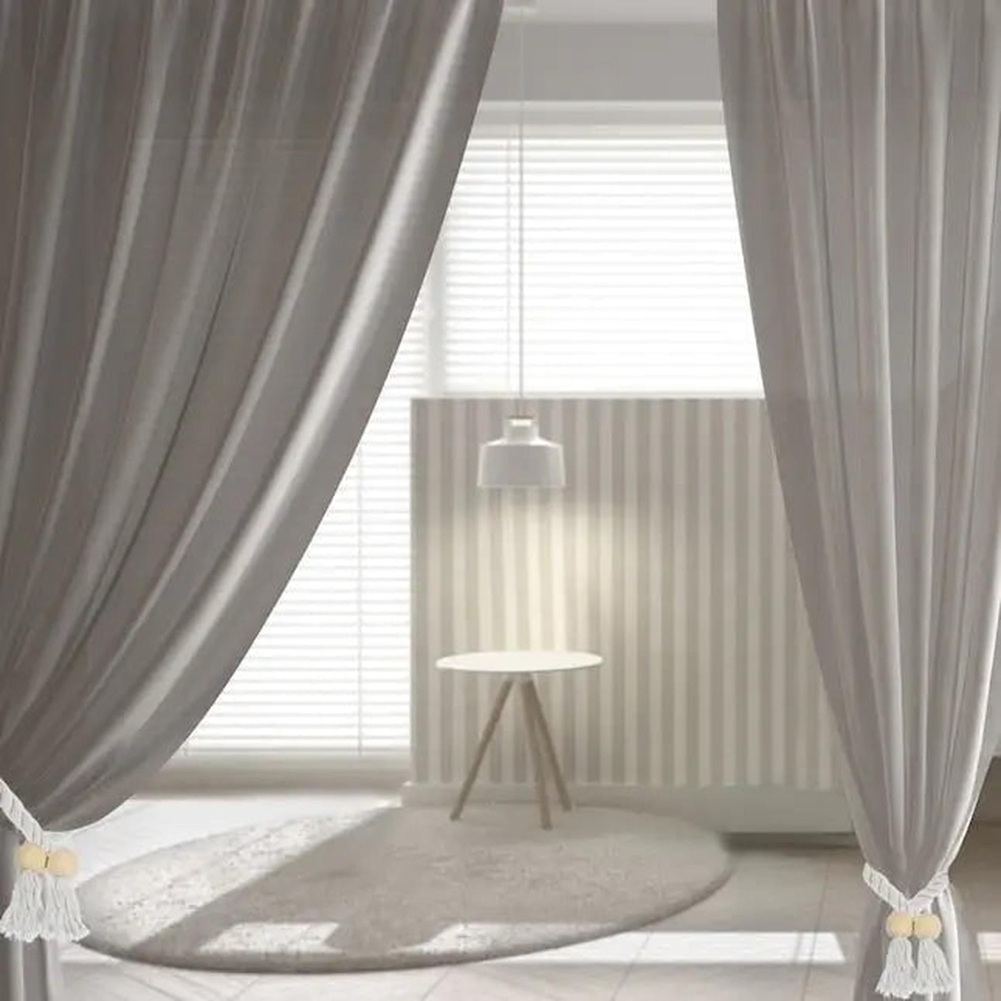 Wooden bead curtain tiebacks with white tassels holding back grey drapes in a modern room.