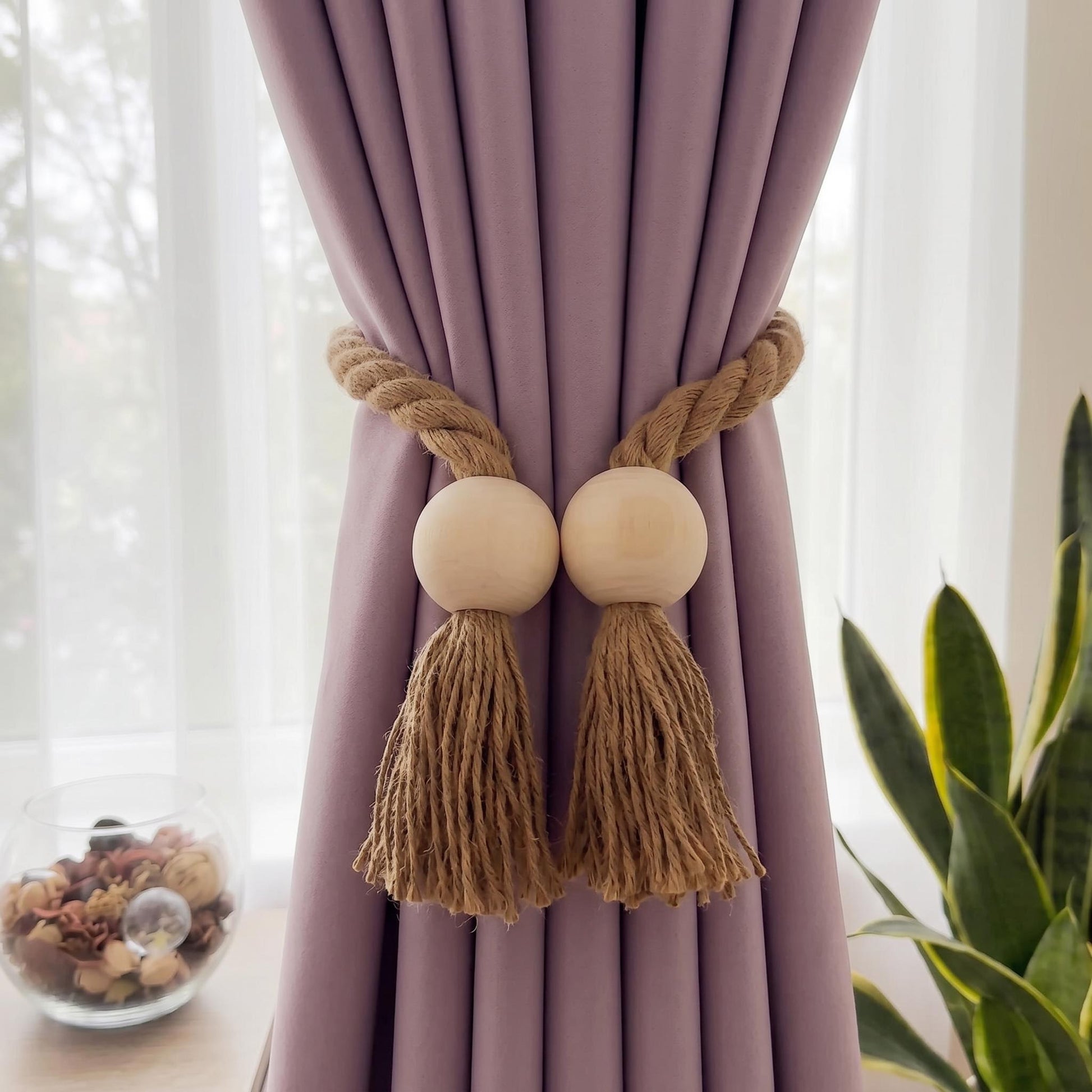 Wooden bead magnetic curtain tieback with brown rope tassels on a lavender curtain.