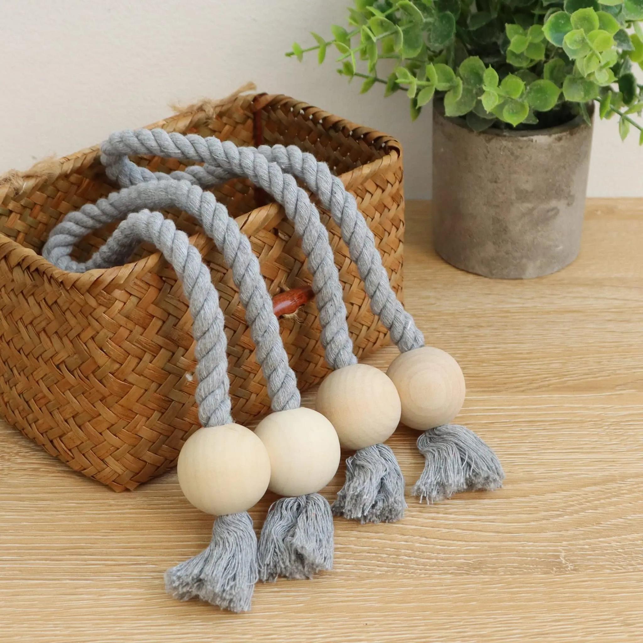 Grey rope curtain tiebacks with wooden beads and tassels draped over a woven basket.