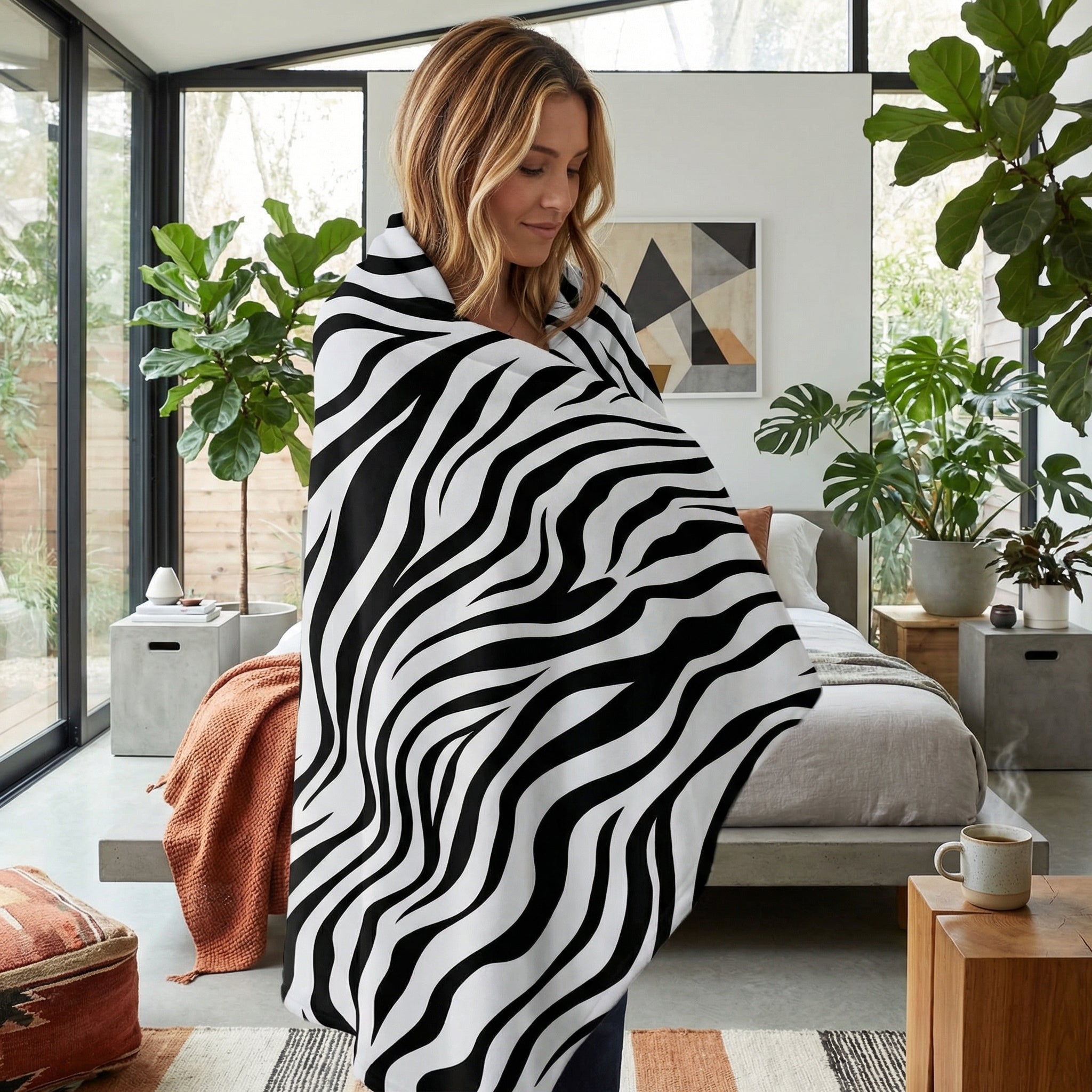 Woman wrapped in a soft, black and white zebra pattern flannel throw blanket in a modern bedroom.