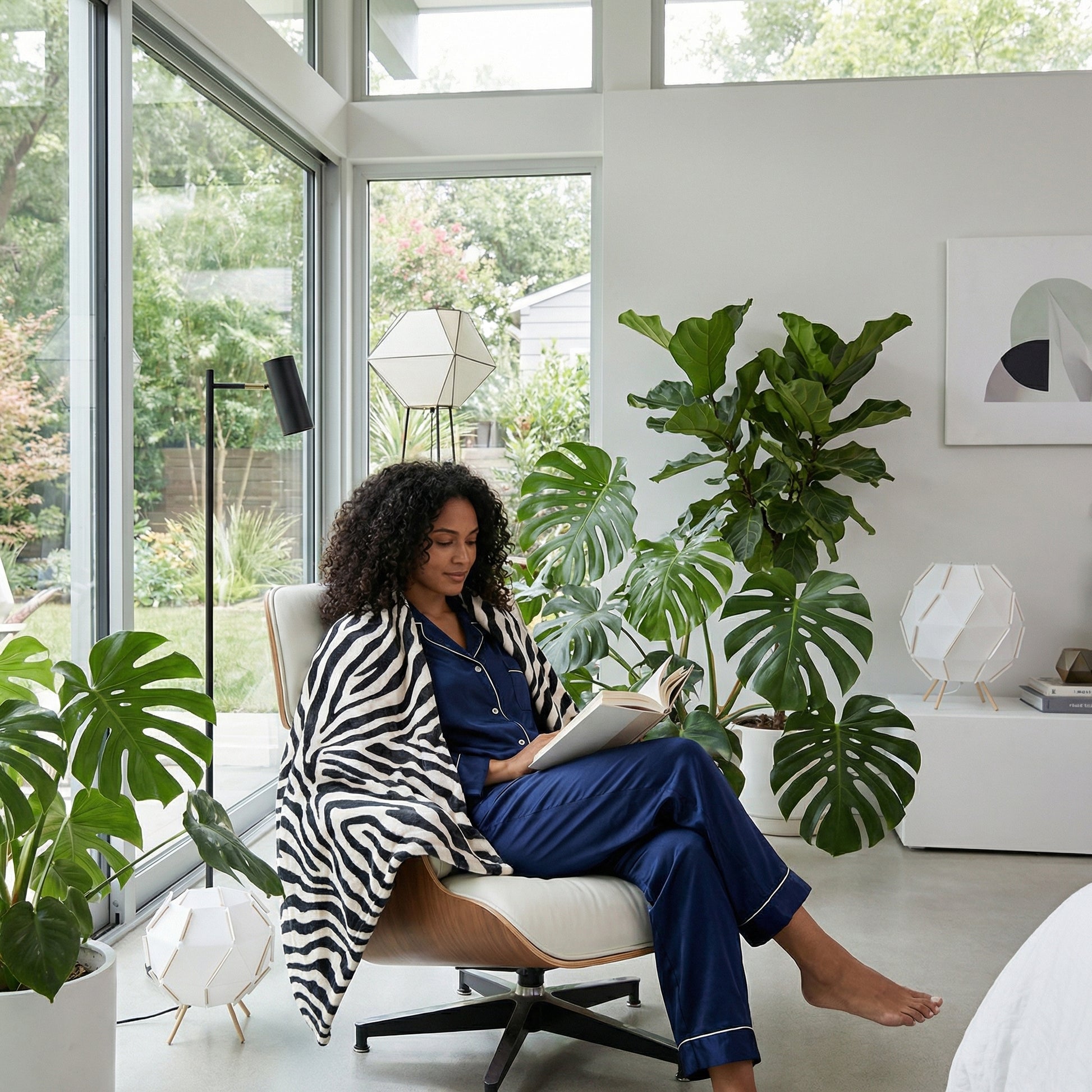 Woman relaxing in a modern room, covered with a soft black and white zebra pattern flannel blanket.