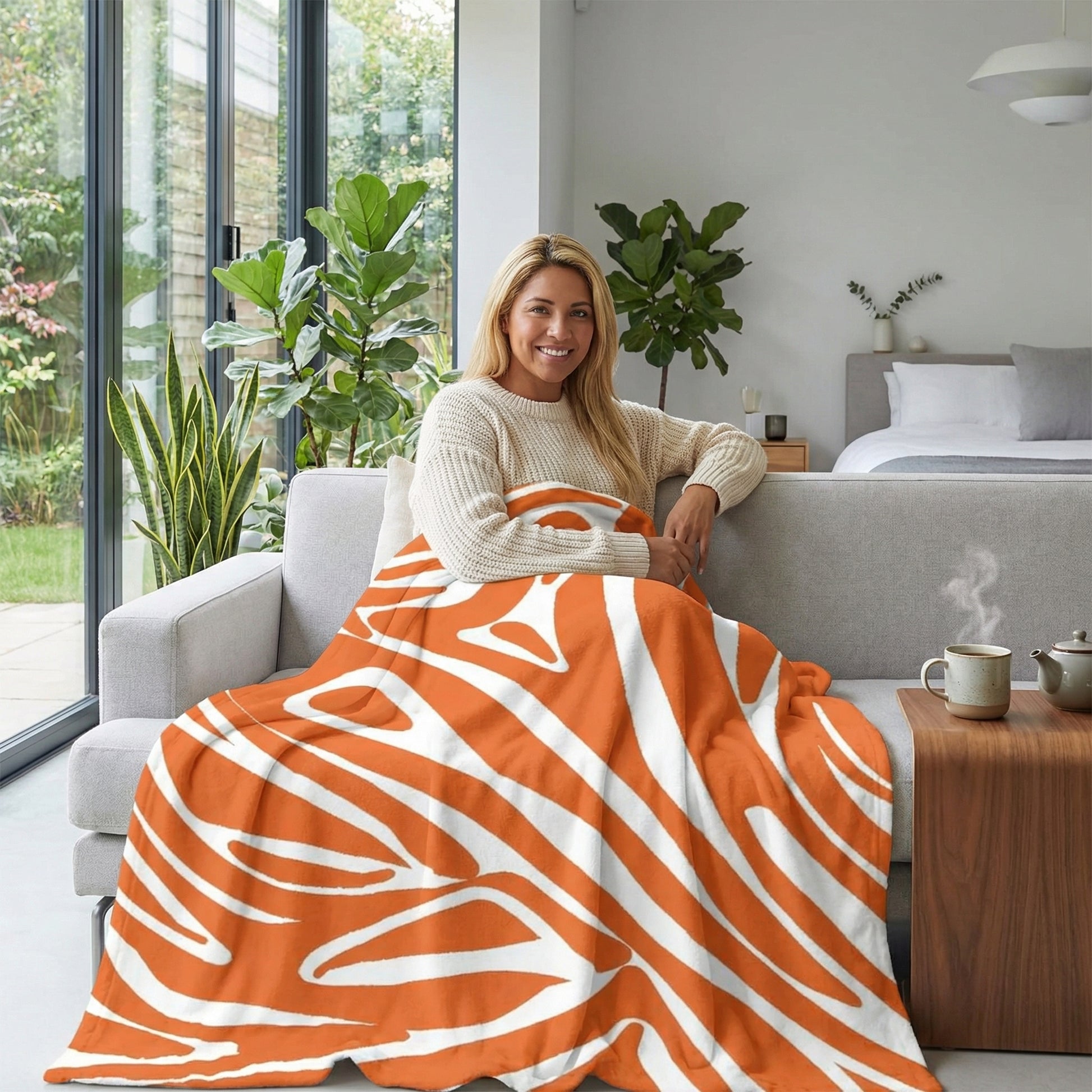 Smiling woman on a sofa covered with an orange and white zebra pattern flannel blanket.